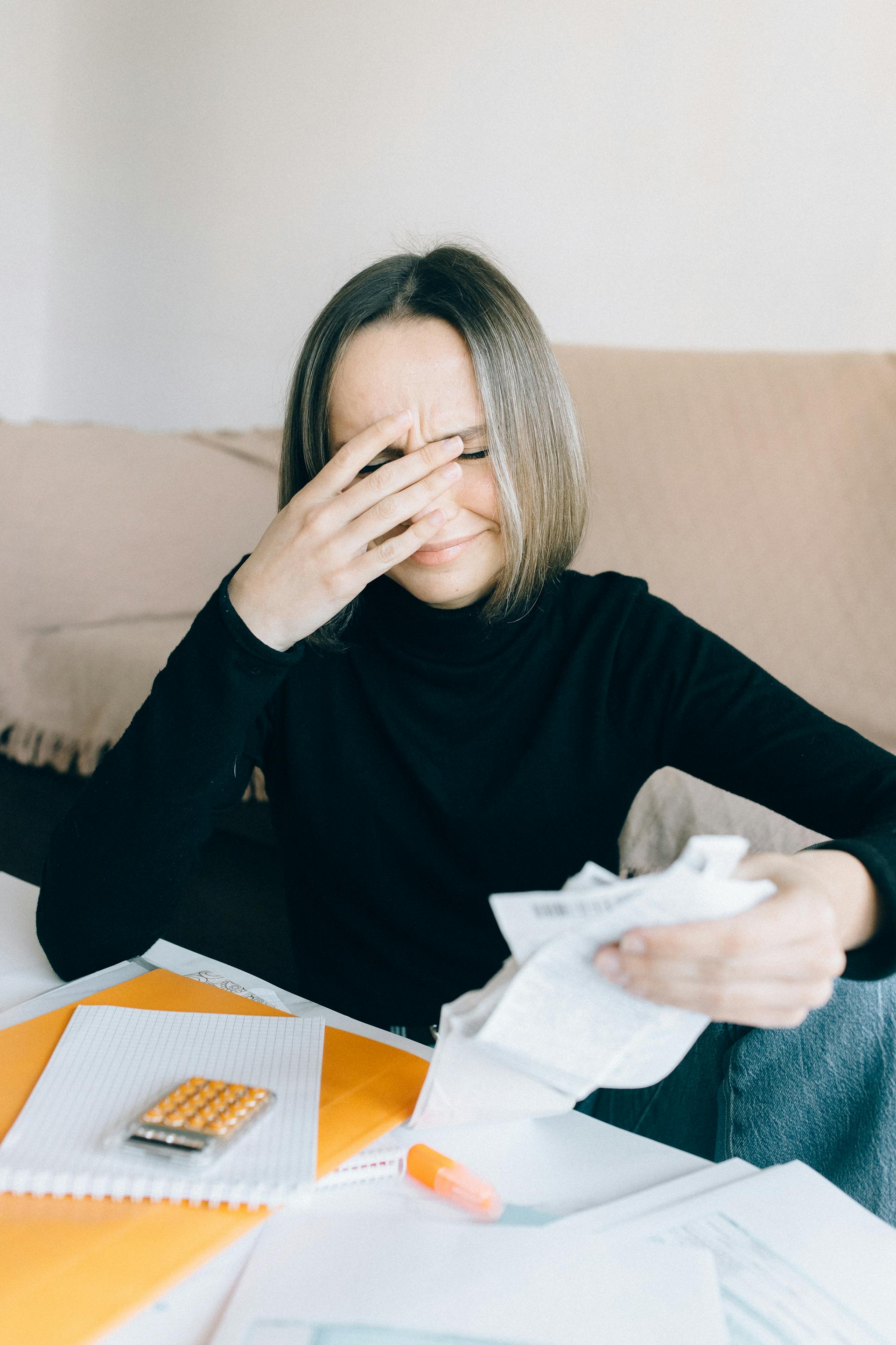 Una mujer emocional sosteniendo unos recibos | Fuente: Pexels
