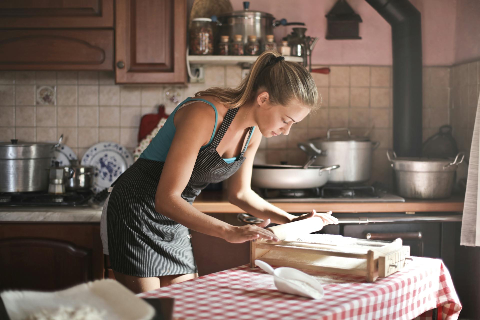 Una joven enrollando masa para hornear en la cocina | Fuente: Pexels