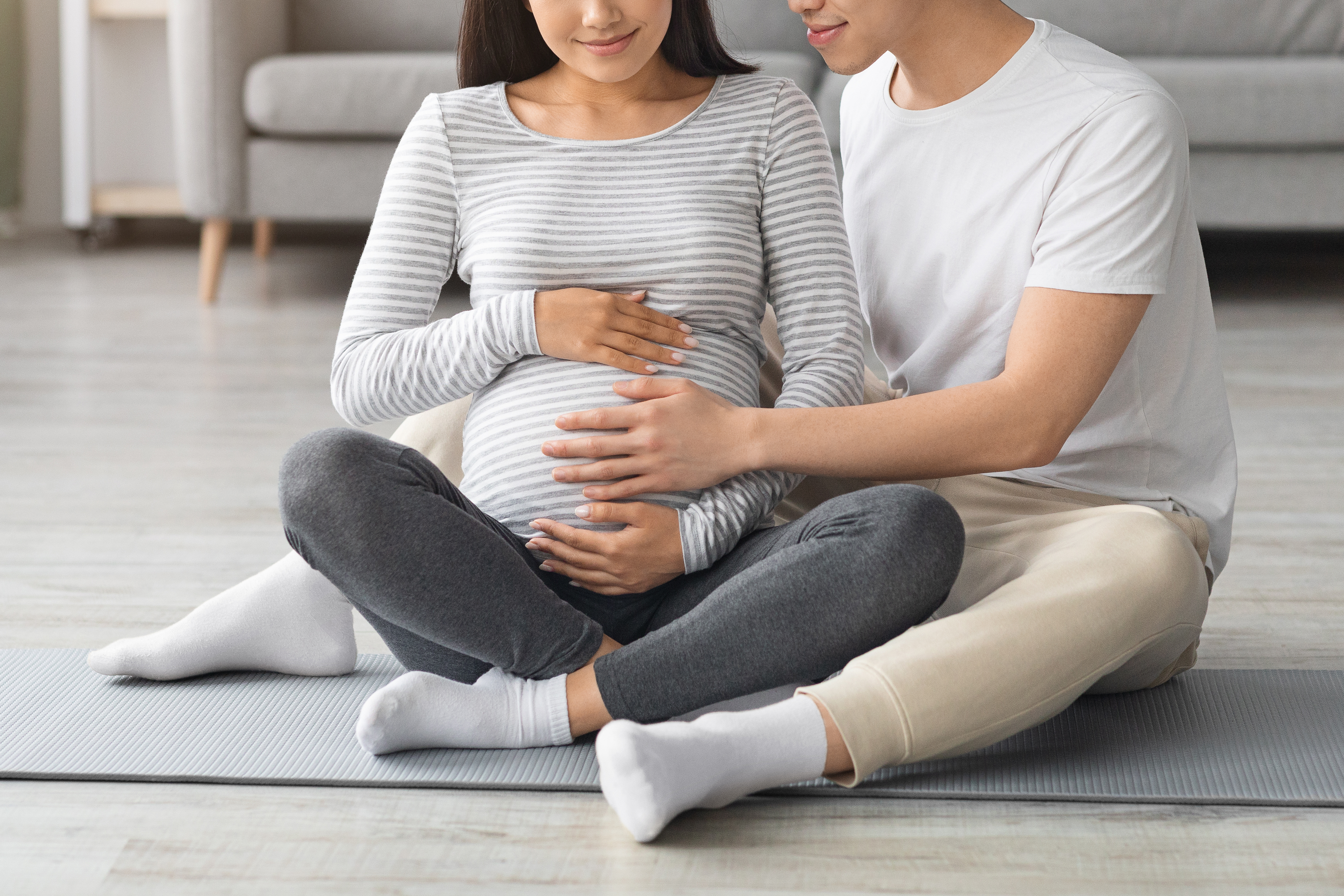 Esposa y marido embarazados sentados en una esterilla de yoga. | Foto: Shutterstock