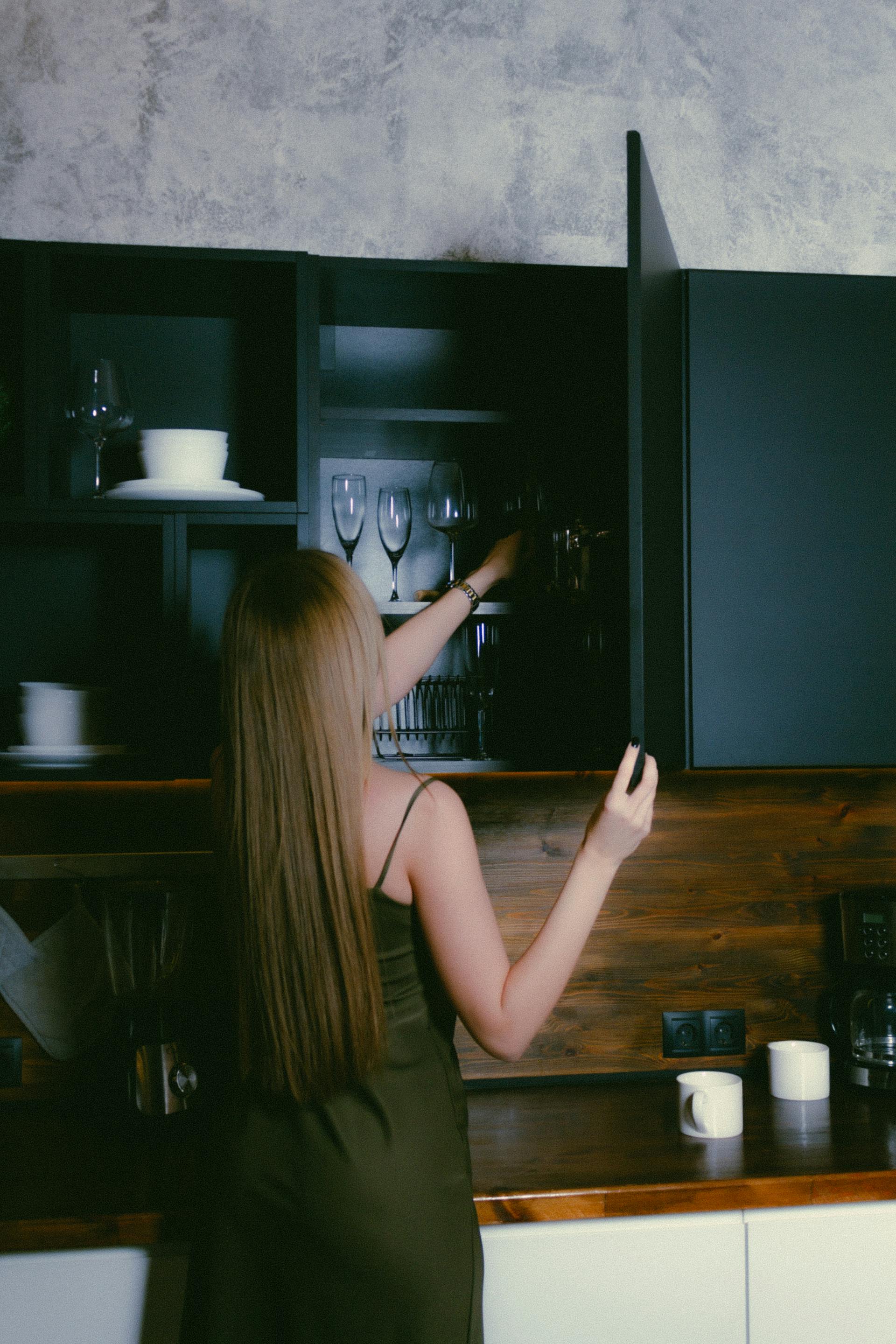 Una mujer empaquetando objetos en los armarios de la cocina | Fuente: Pexels