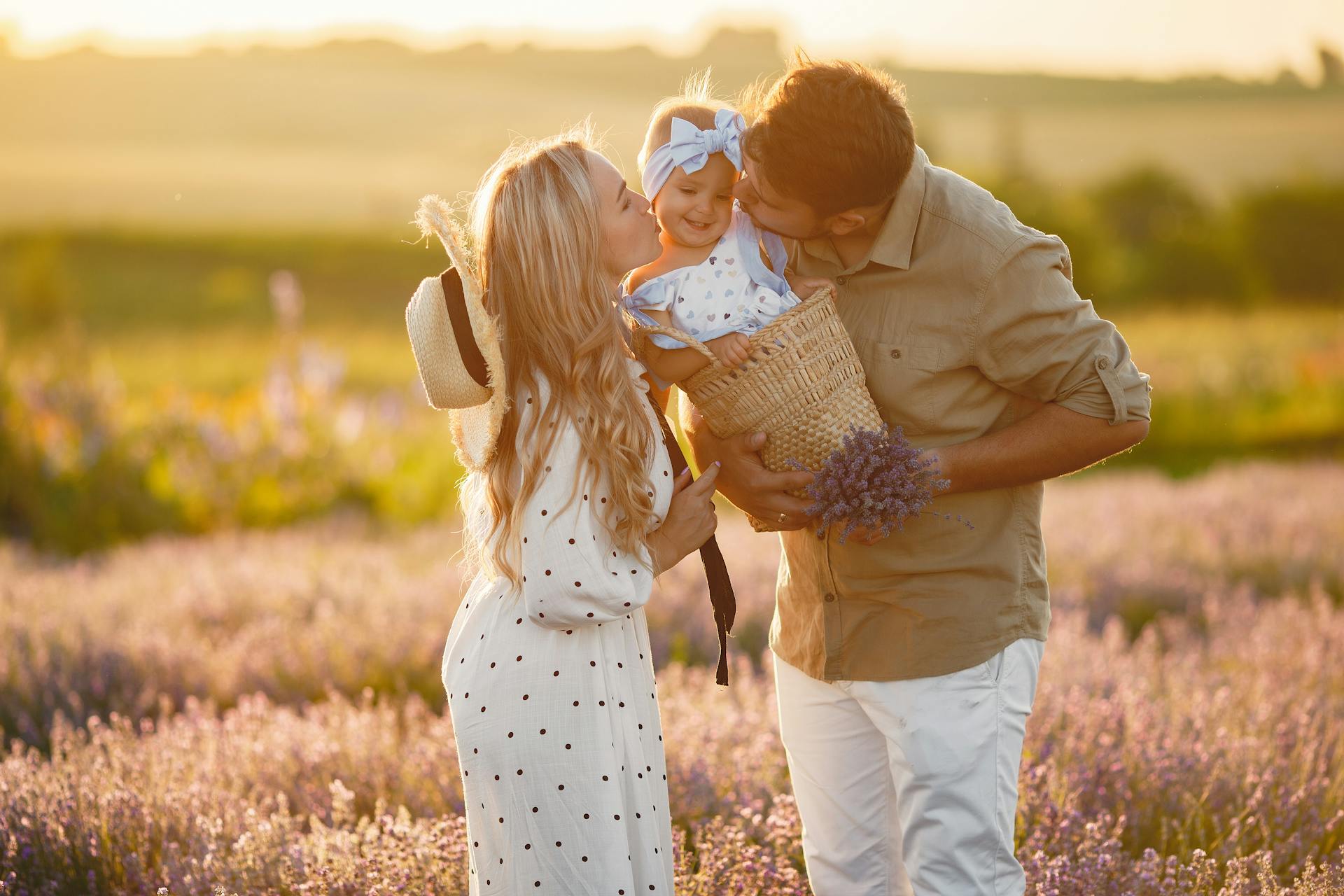 Una pareja besando a su hija pequeña en un campo de lavanda | Fuente: Pexels