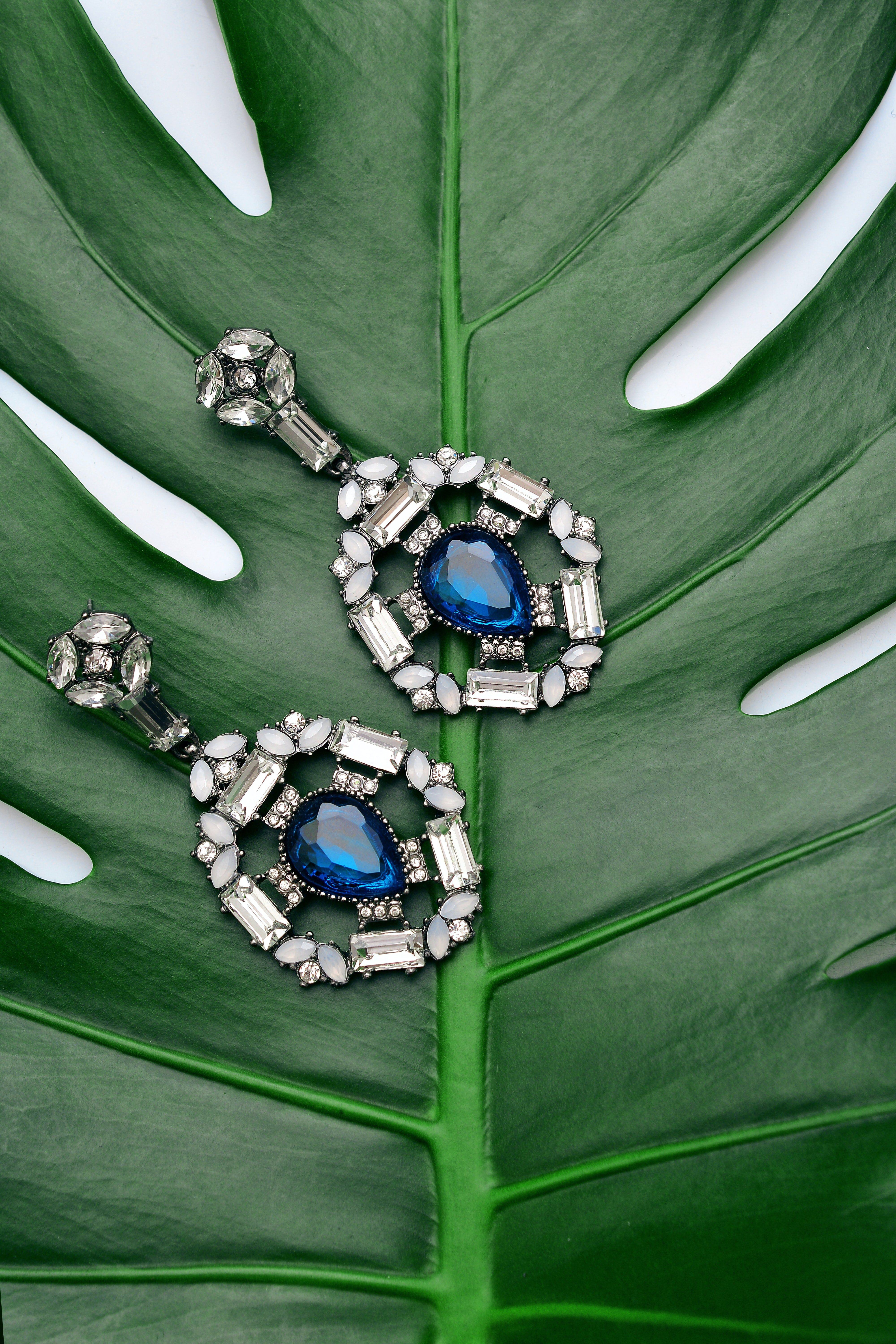Unos pendientes con piedras azules y brillantes sobre una hoja verde. | Foto: Unsplash