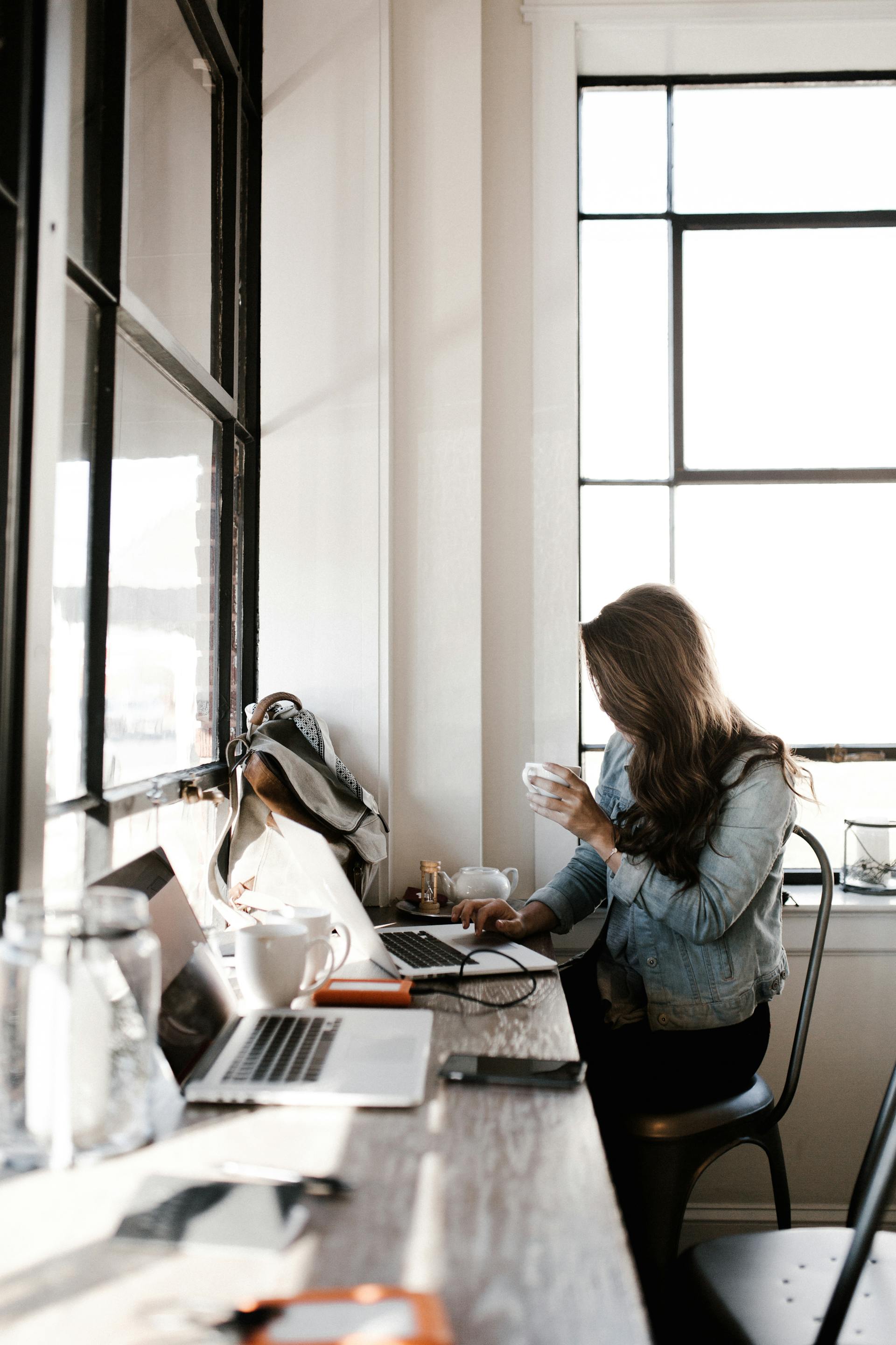 Una joven trabajando con su portátil sentada junto a un escritorio | Fuente: Pexels
