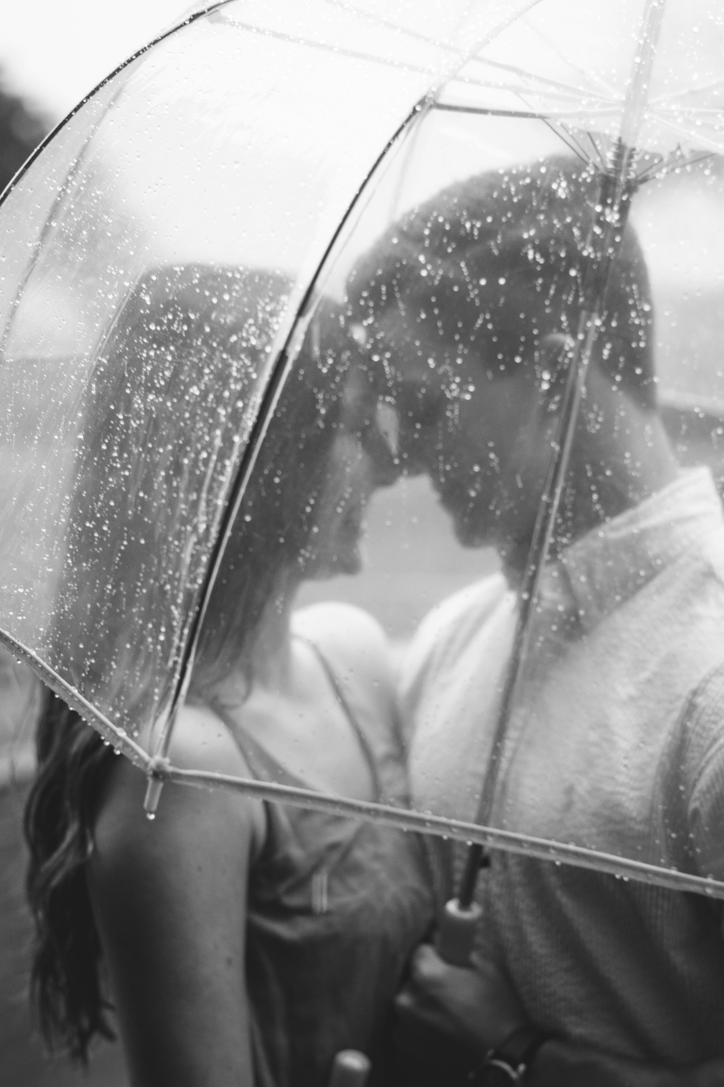 Una joven pareja romántica bajo un paraguas transparente en un día lluvioso | Fuente: Unsplash