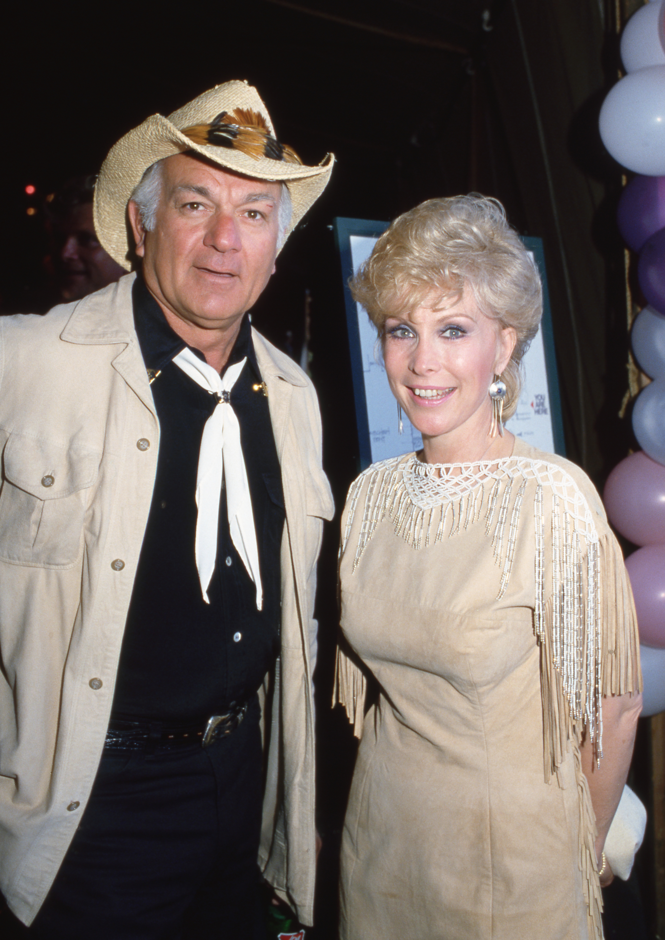 Barbara Eden lleva un conjunto blanco y crema junto a Robert Mandan en una fiesta en 1982. | Fuente: Getty Images