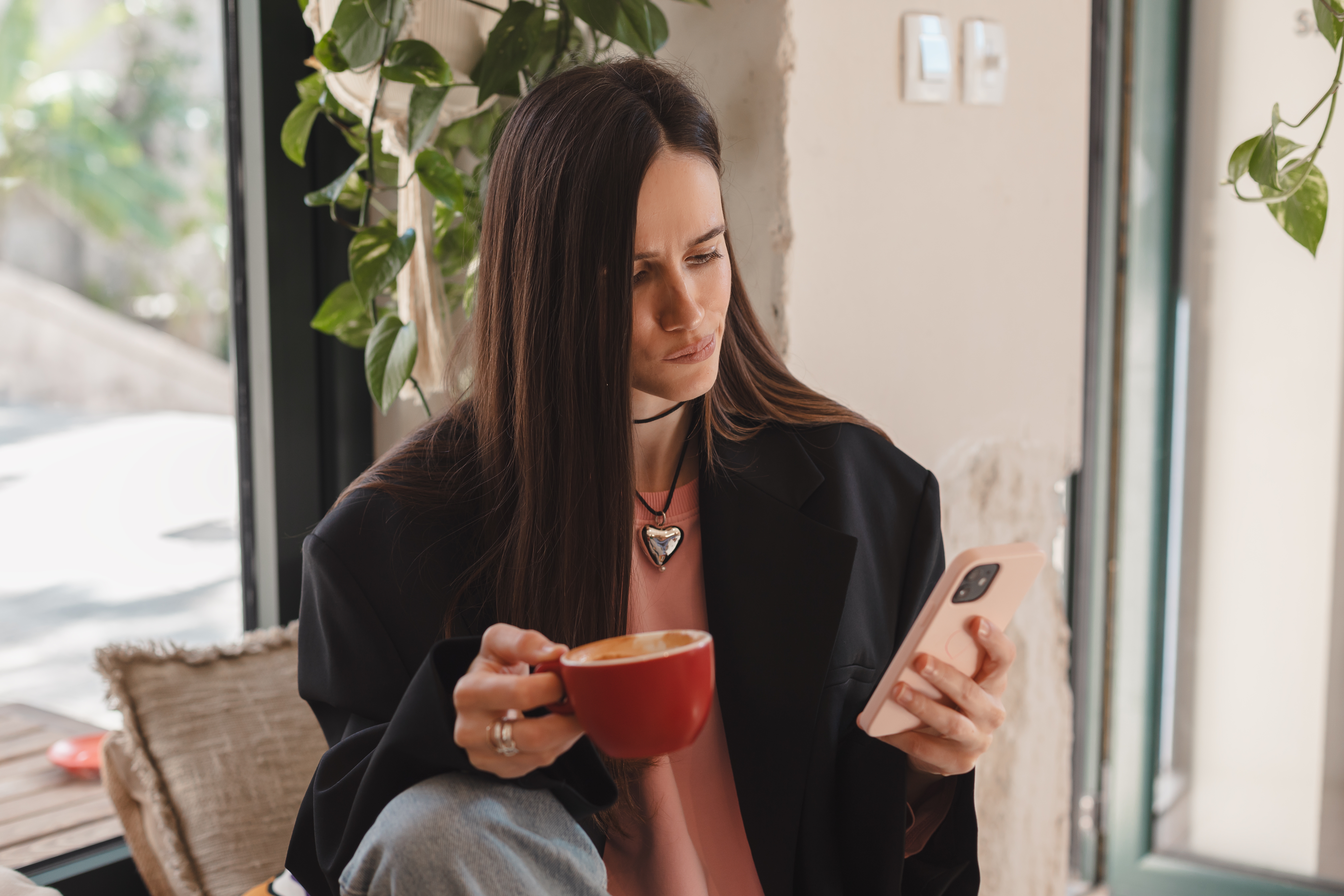 Mujer con su teléfono sostiene una taza de café | Fuente: Shutterstock