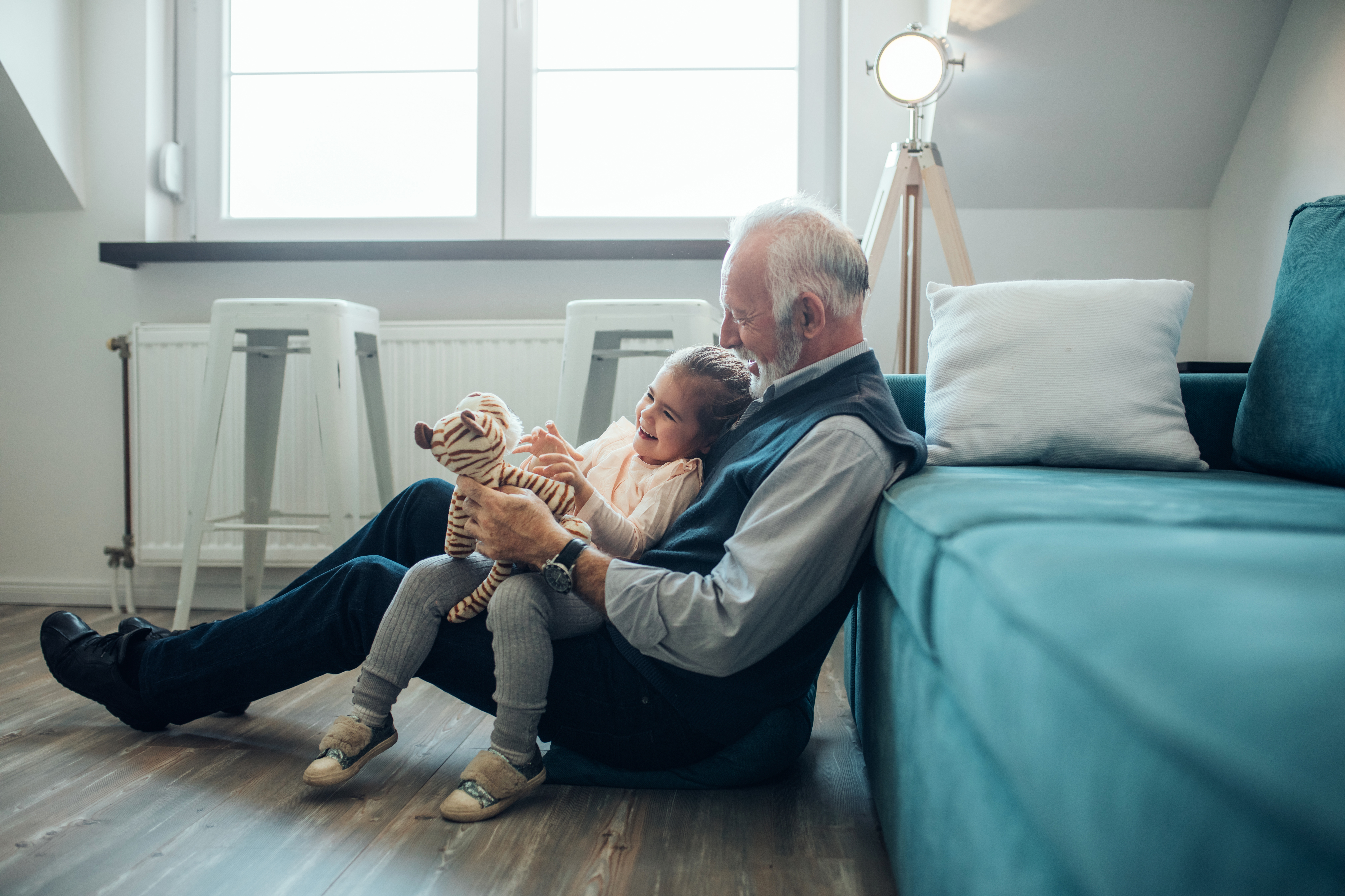 Un abuelo sentado en el suelo con su nieta en el regazo | Foto: Shutterstock