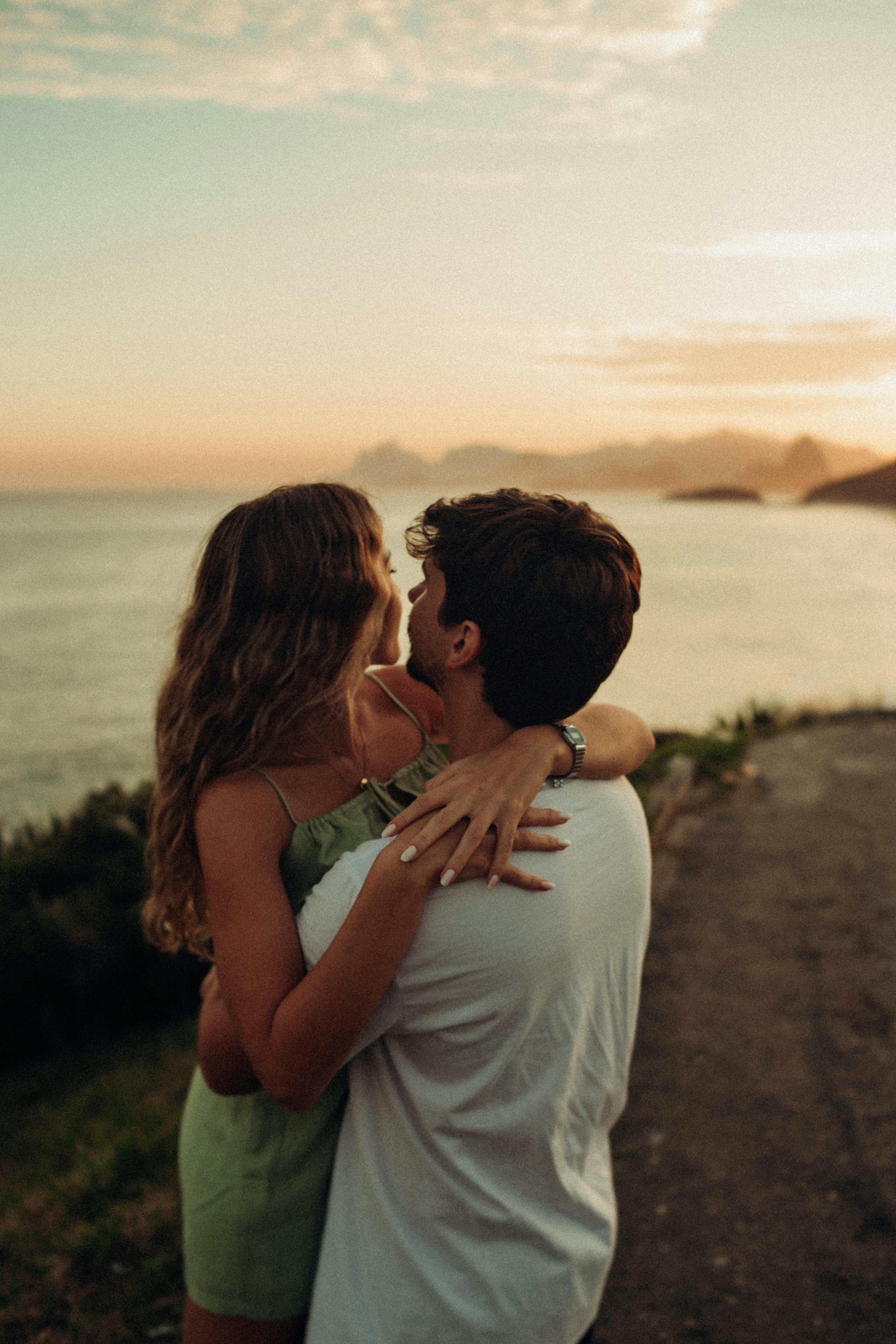 Una pareja abrazándose en la playa al atardecer | Foto: Pexels