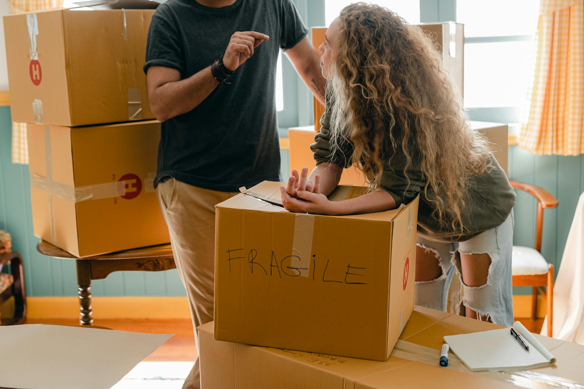 Una pareja hablando en medio de una pila de cajas de cartón embaladas | Fuente: Pexels