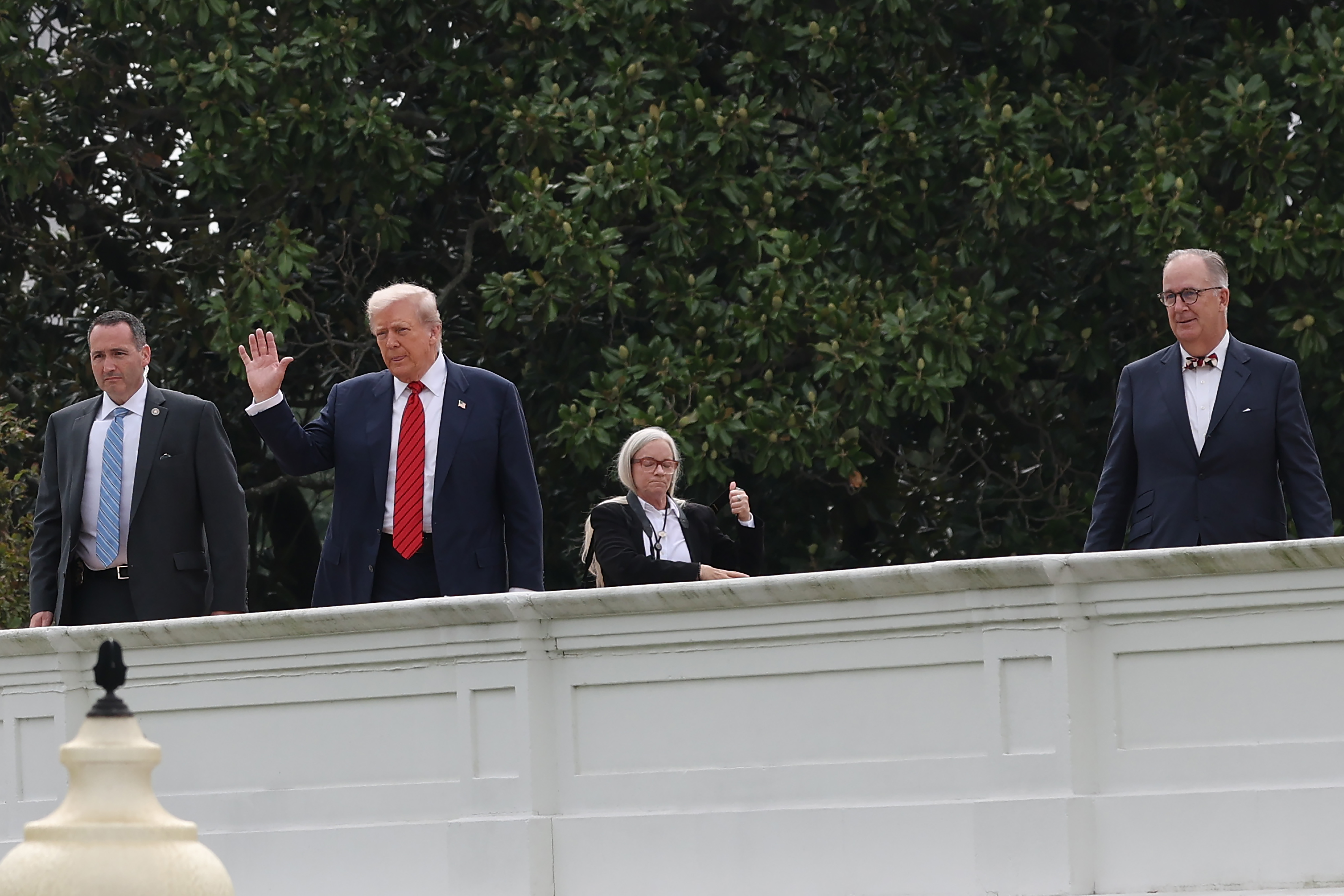 Saludando a los periodistas desde el techo, el presidente Donald Trump se encuentra junto al arquitecto James C. McCrery y el personal de seguridad durante su sorprendente paseo por la cima de la mansión ejecutiva.
