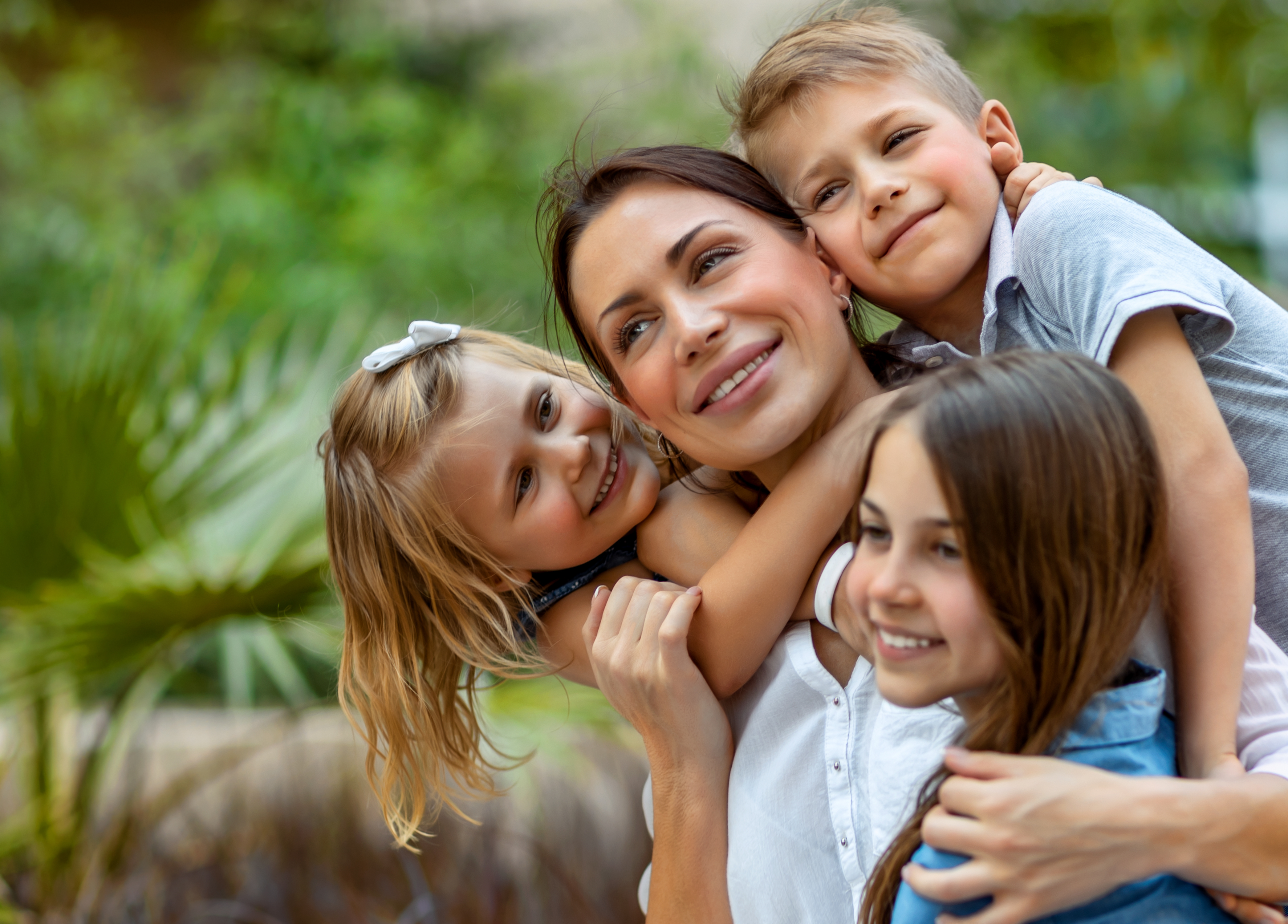 Una joven mamá abraza a sus tres hijos pequeños. | Foto: Shutterstock