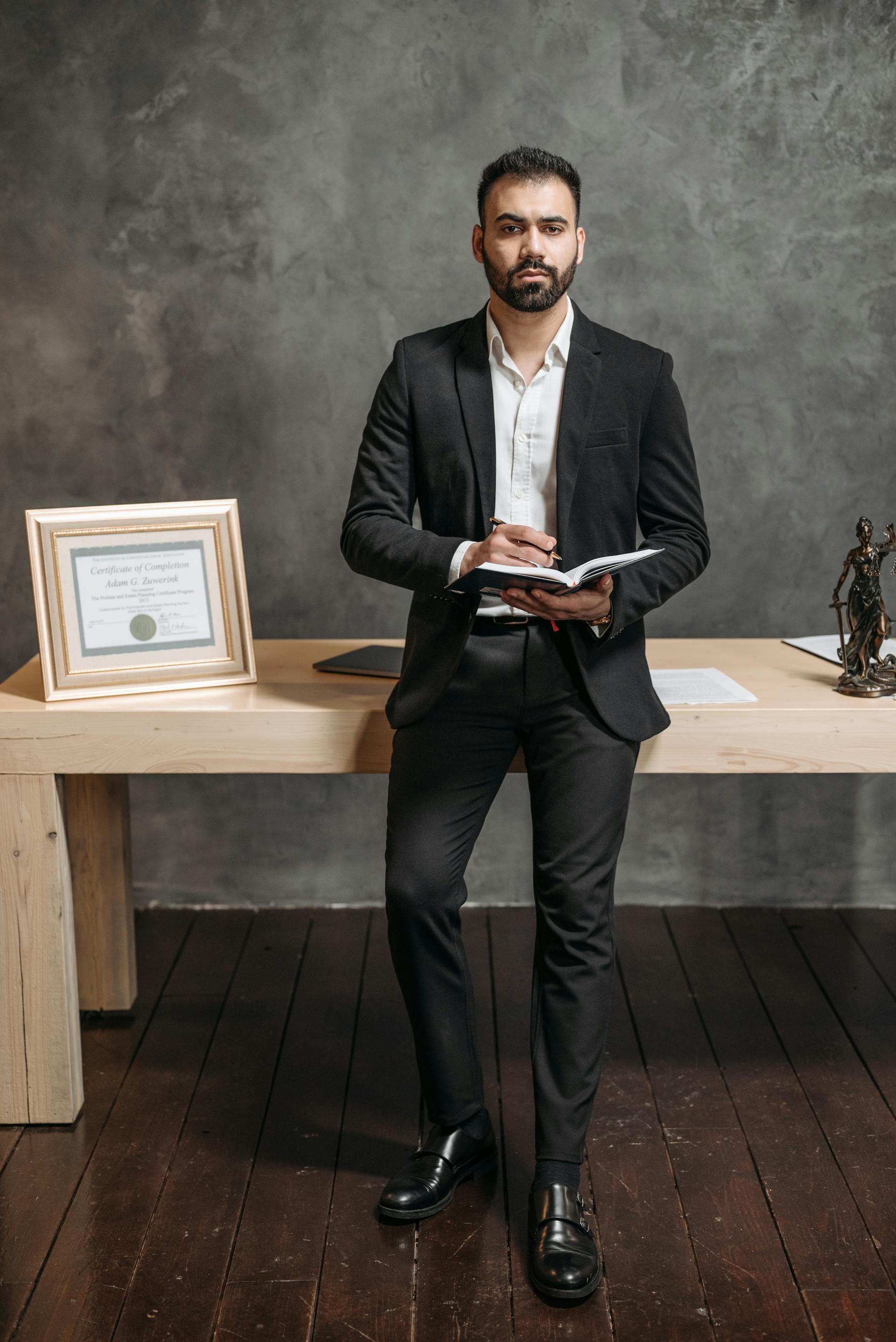 Uomo in abito nero con un taccuino in mano | Fonte: Pexels
