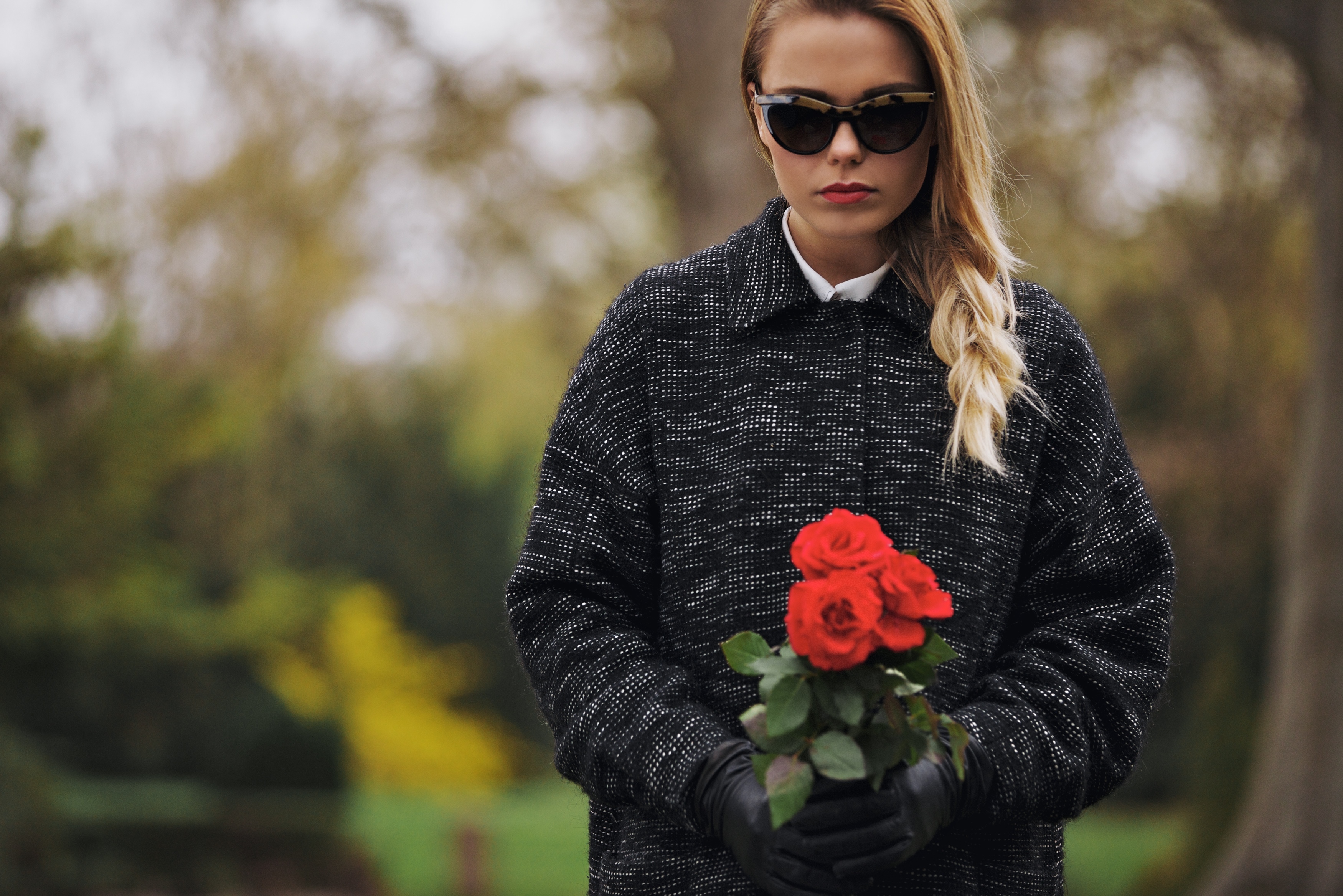 Retrato de mujer joven con vestido negro en un cementerio sosteniendo flores frescas. | Fuente: Shutterstock
