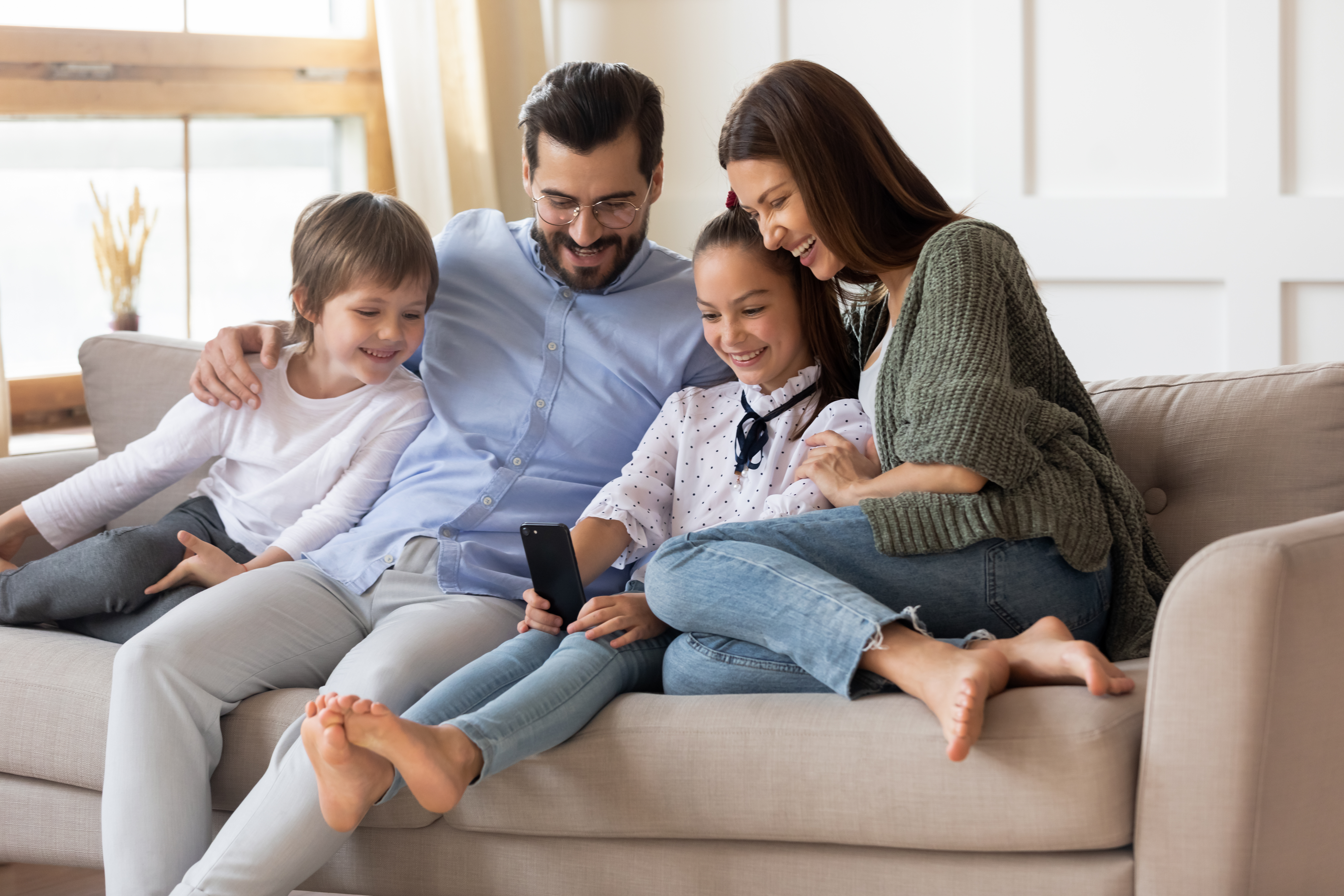 Padres felices relajándose en casa con sus hijos pequeños | Foto: Shutterstock