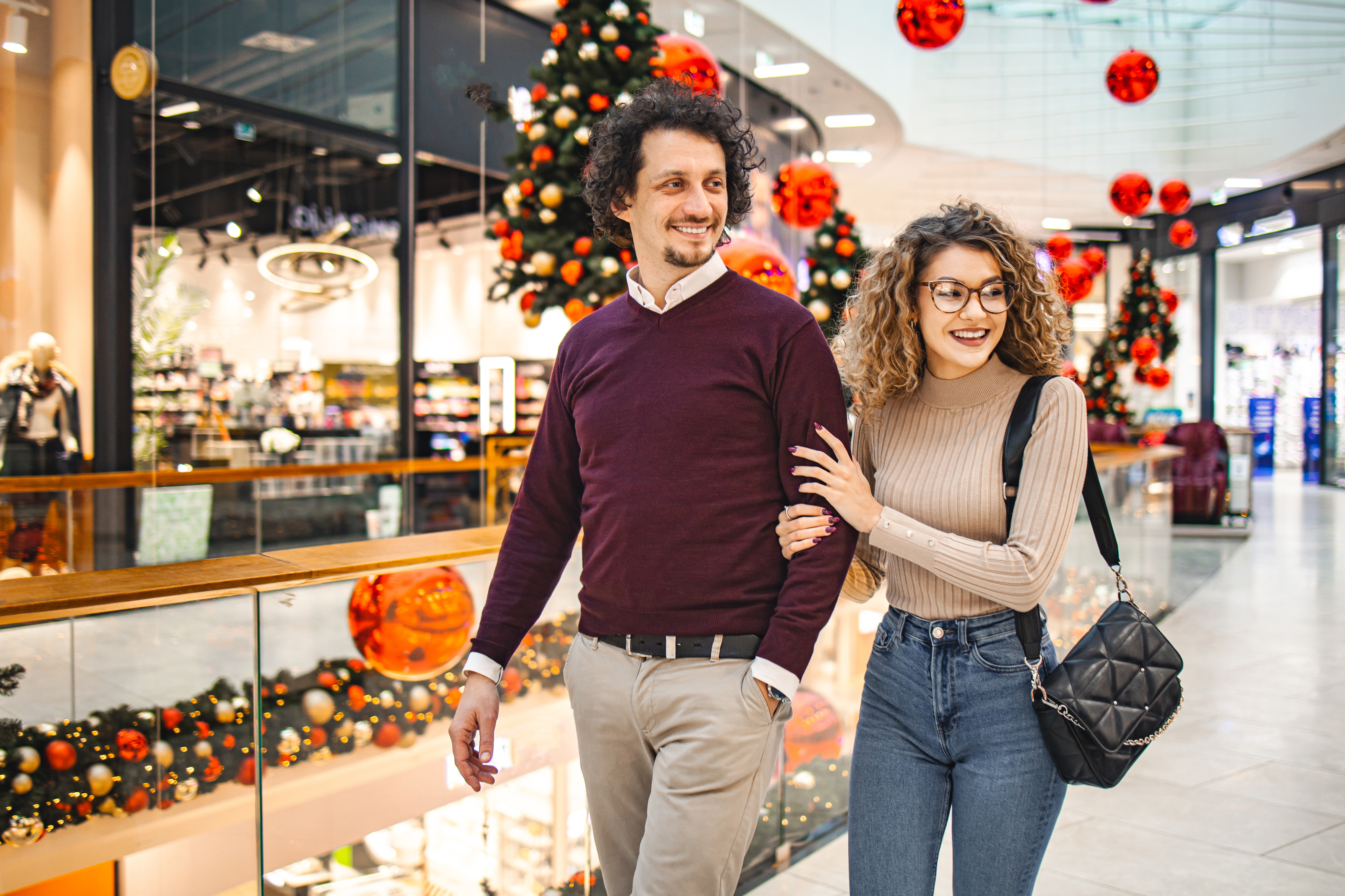 Pareja joven en el centro comercial comprando regalos de Navidad | Fuente: Getty Images