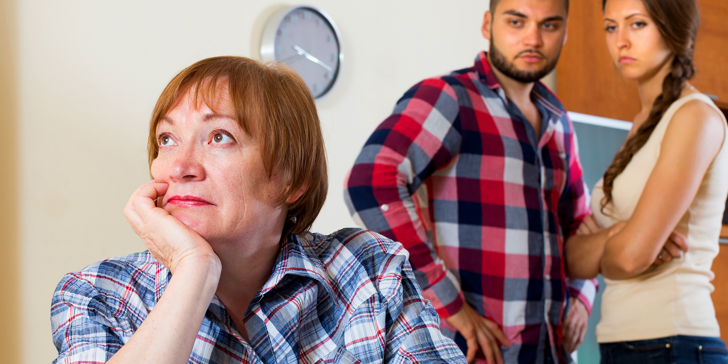 Mujer mayor pensativa con una pareja de fondo | Foto: Shutterstock