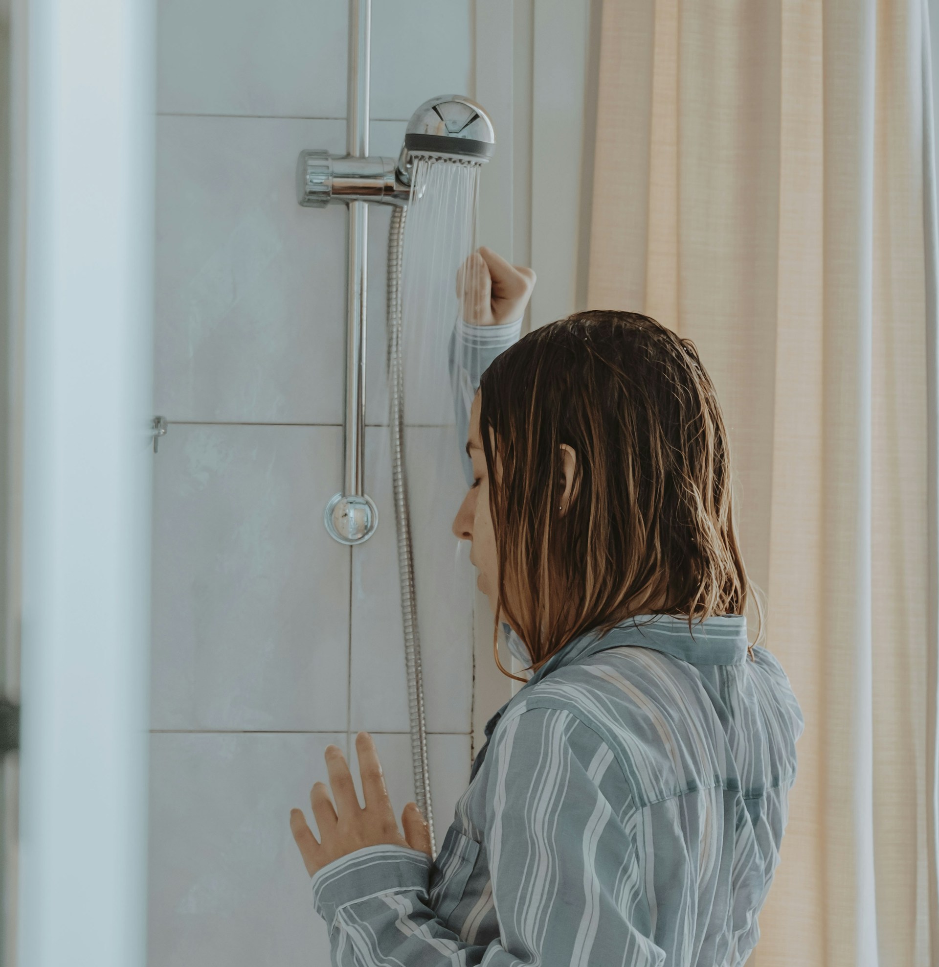 Una joven deprimida y desesperada de pie en la ducha | Fuente: Unsplash