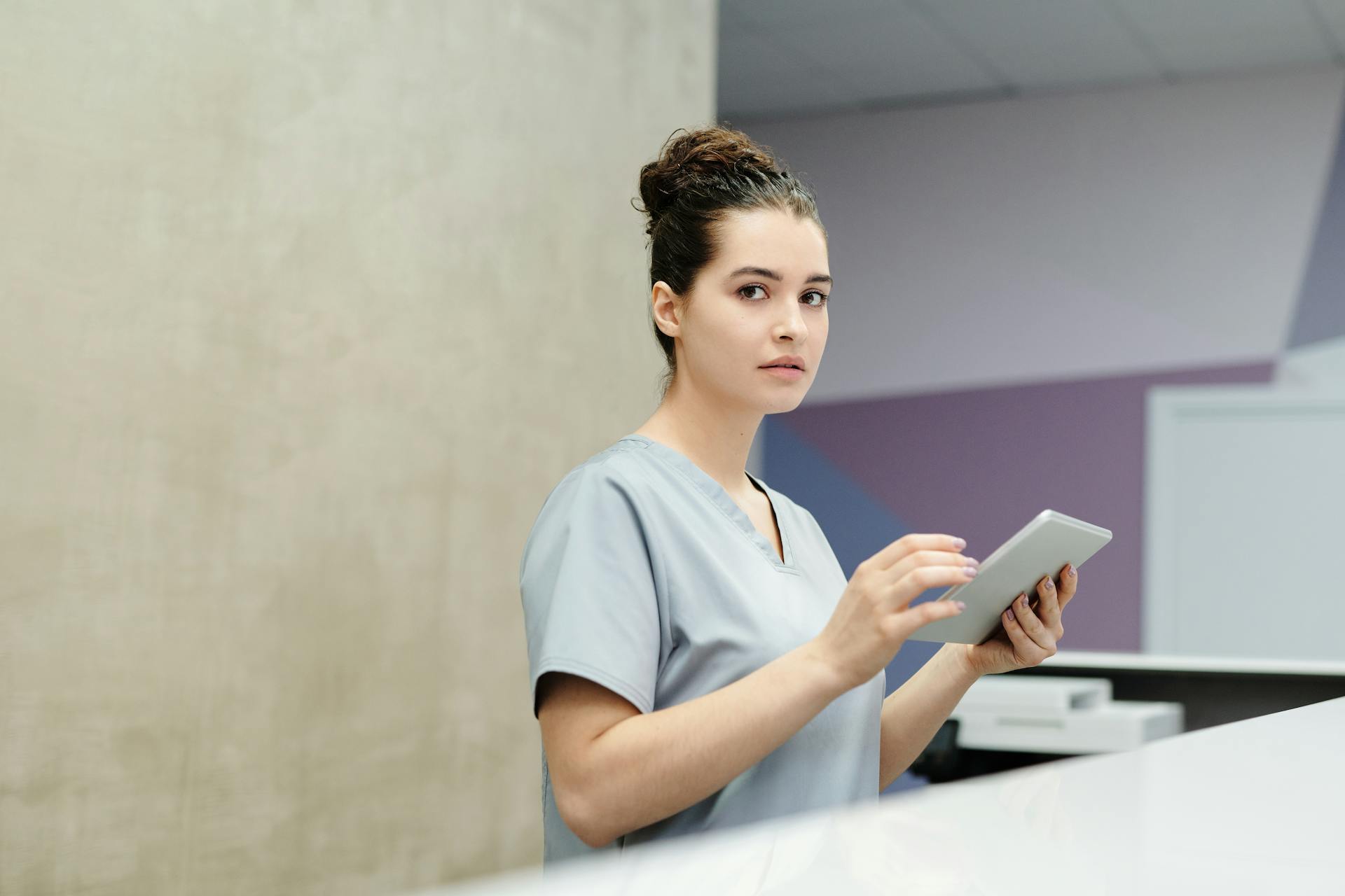 Una recepcionista sujetando un ordenador tablet en un hospital | Fuente: Pexels