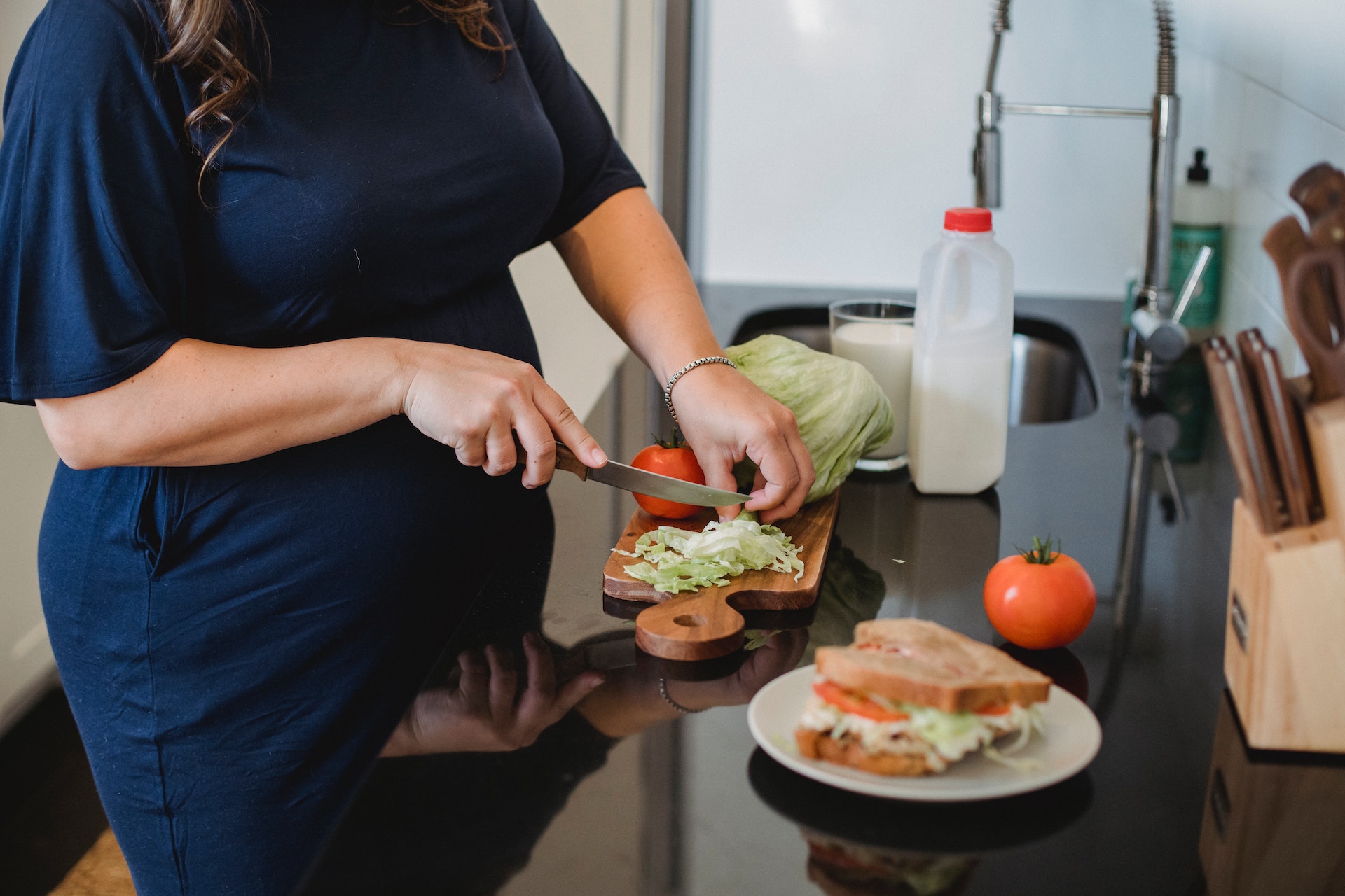 Una mujer embarazada cortando verduras. | Foto: Pexels