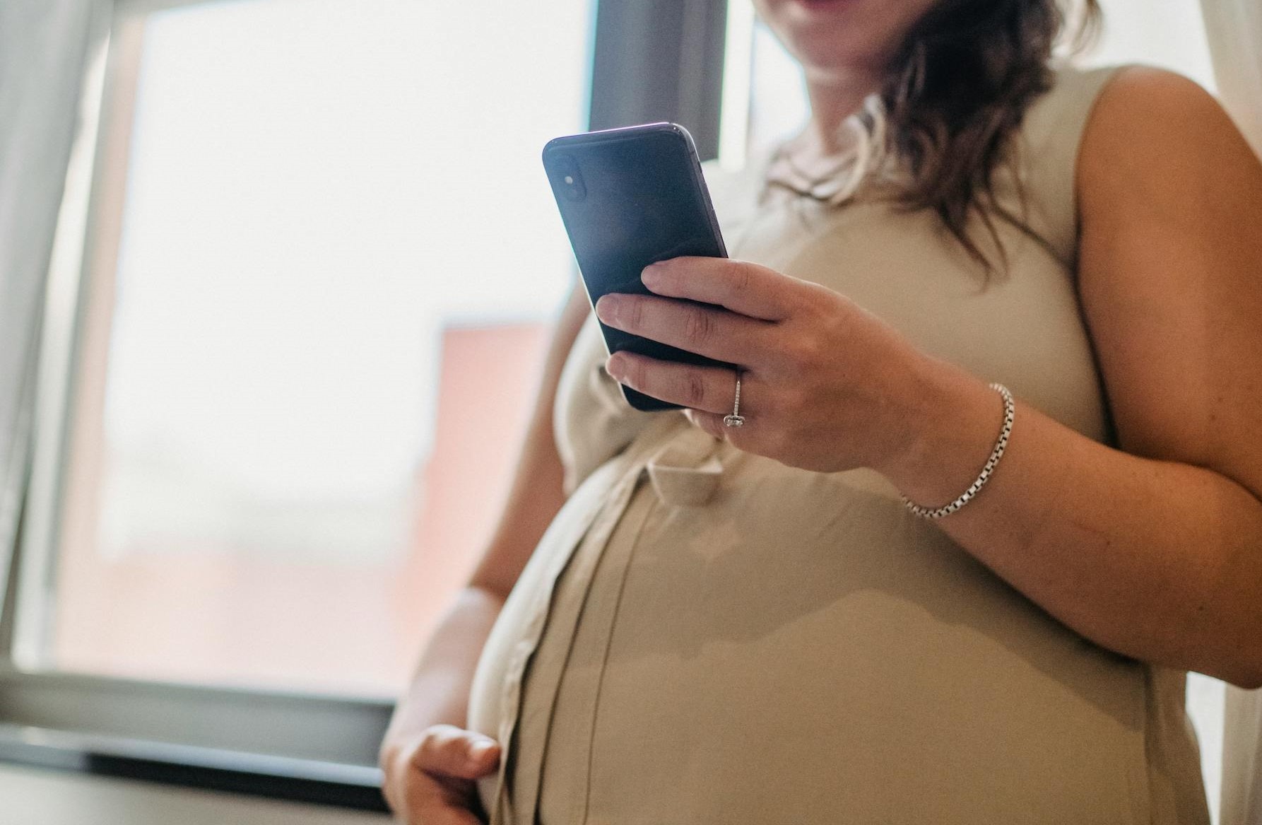 Una mujer embarazada sujetando un smartphone | Fuente: Pexels