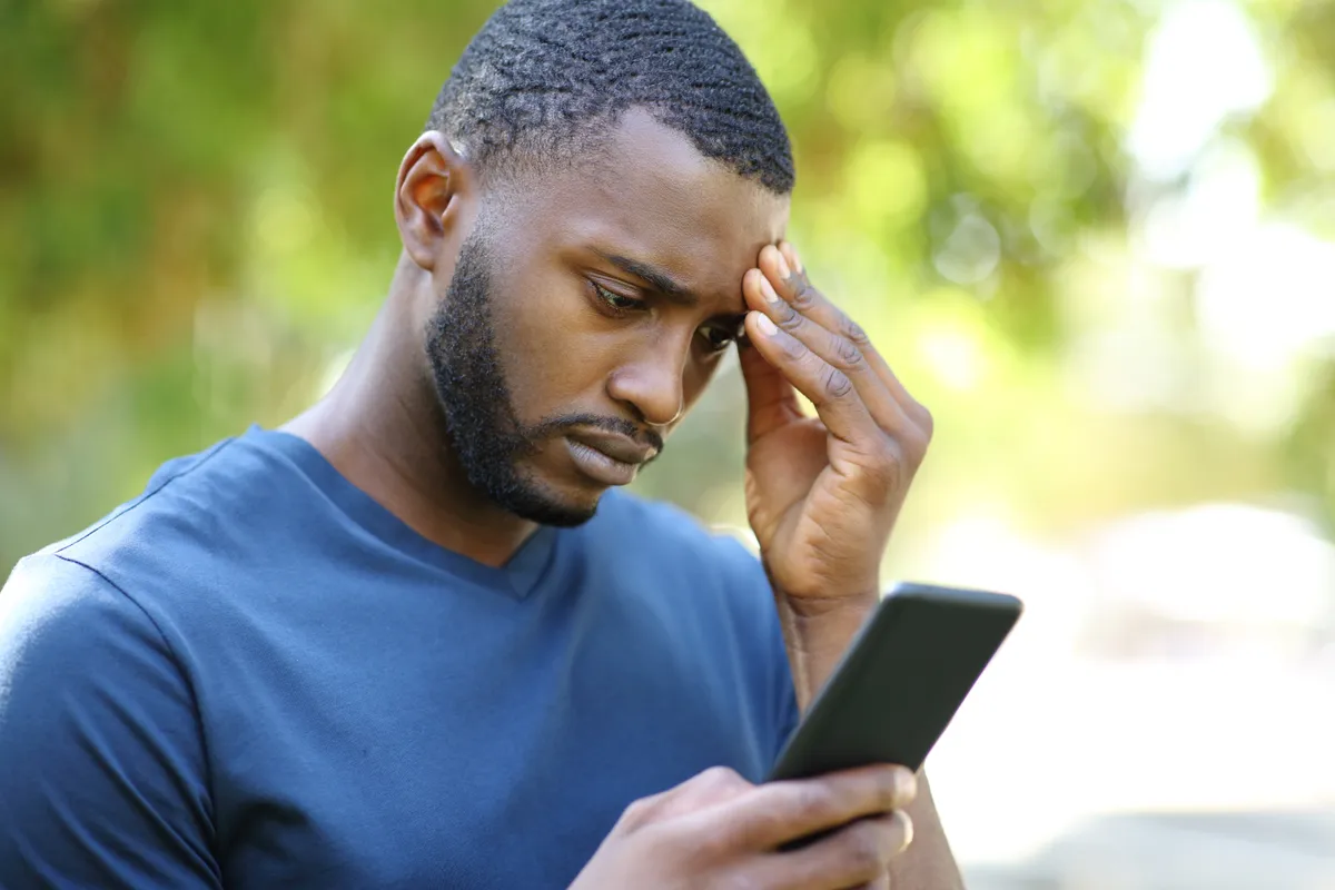 Hombre revisando su smartphone en un parque | Fuente: Getty Images