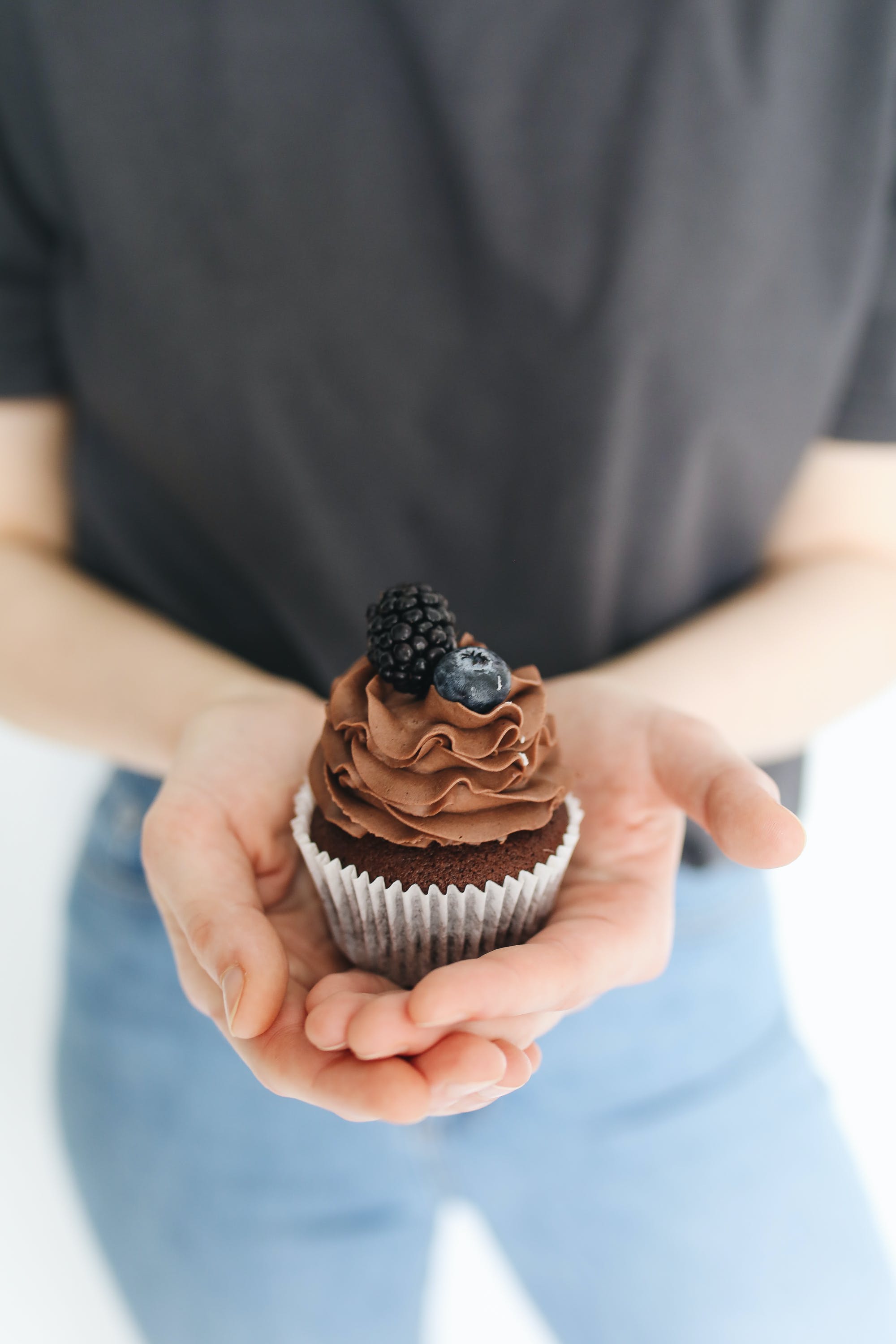 Una persona con una magdalena de chocolate en la mano. | Fuente: Pexels