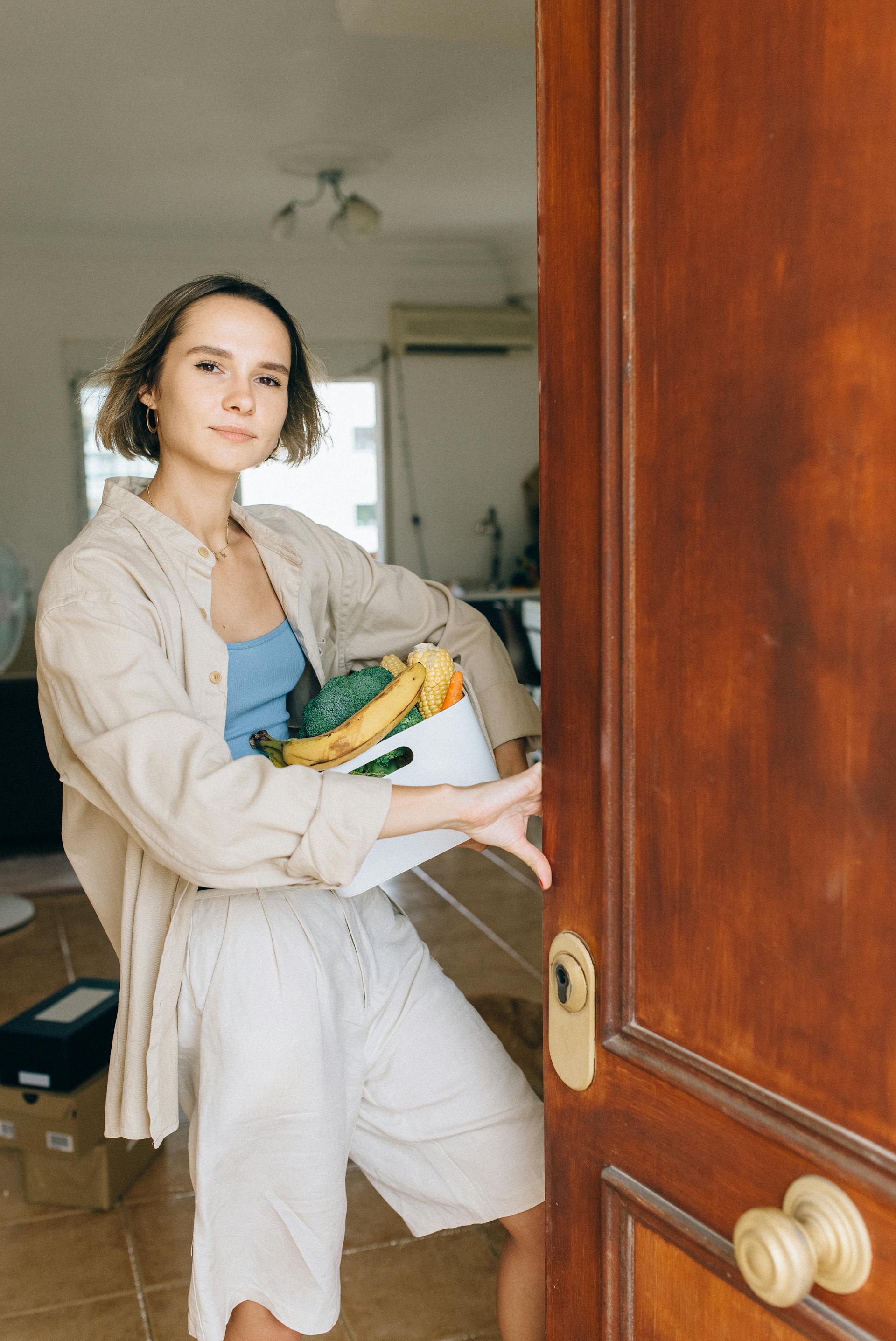 Una mujer de pie en la puerta abierta de su Apartamento | Fuente: Pexels