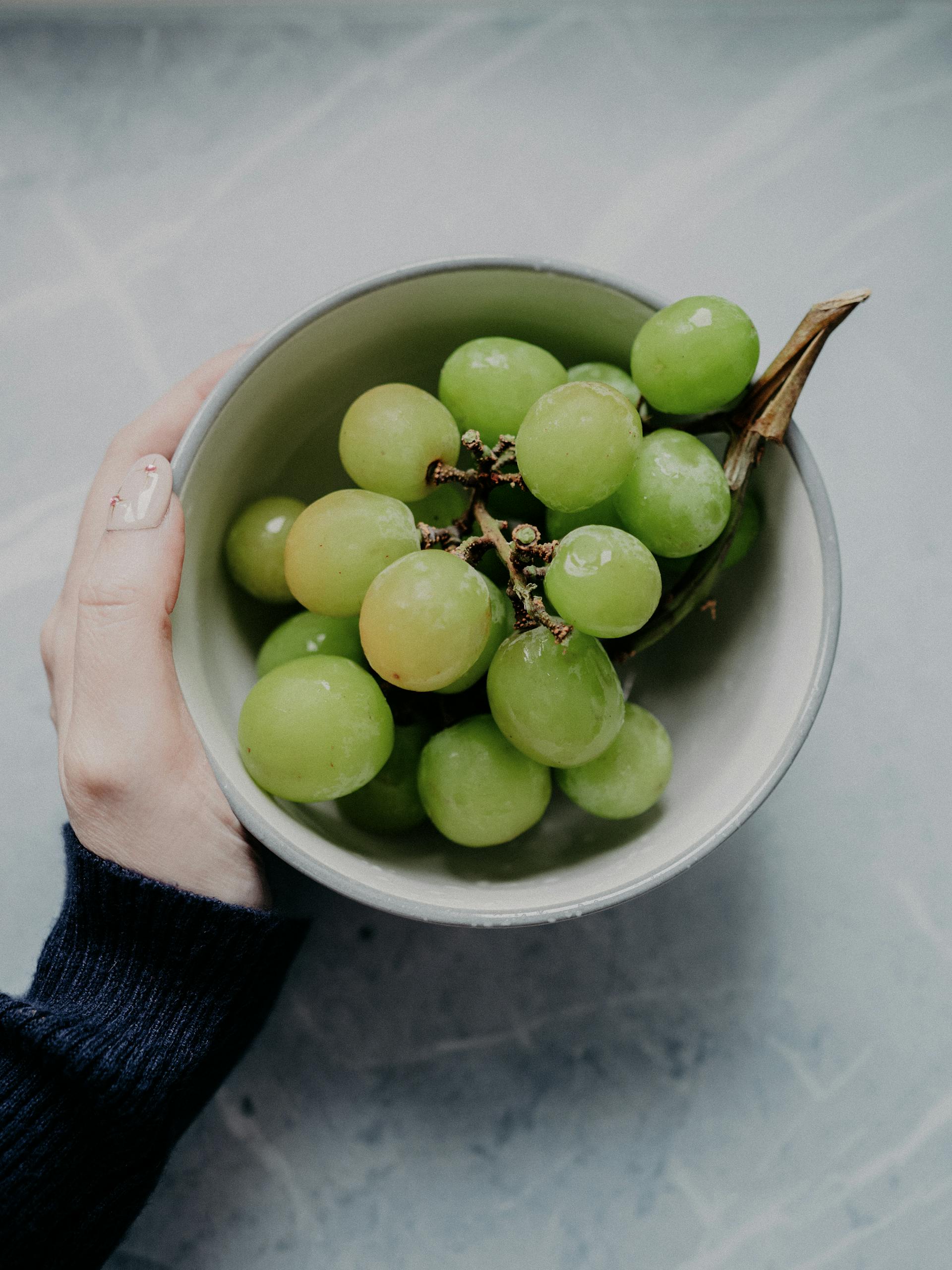 Una persona con un cuenco de uvas | Fuente: Pexels