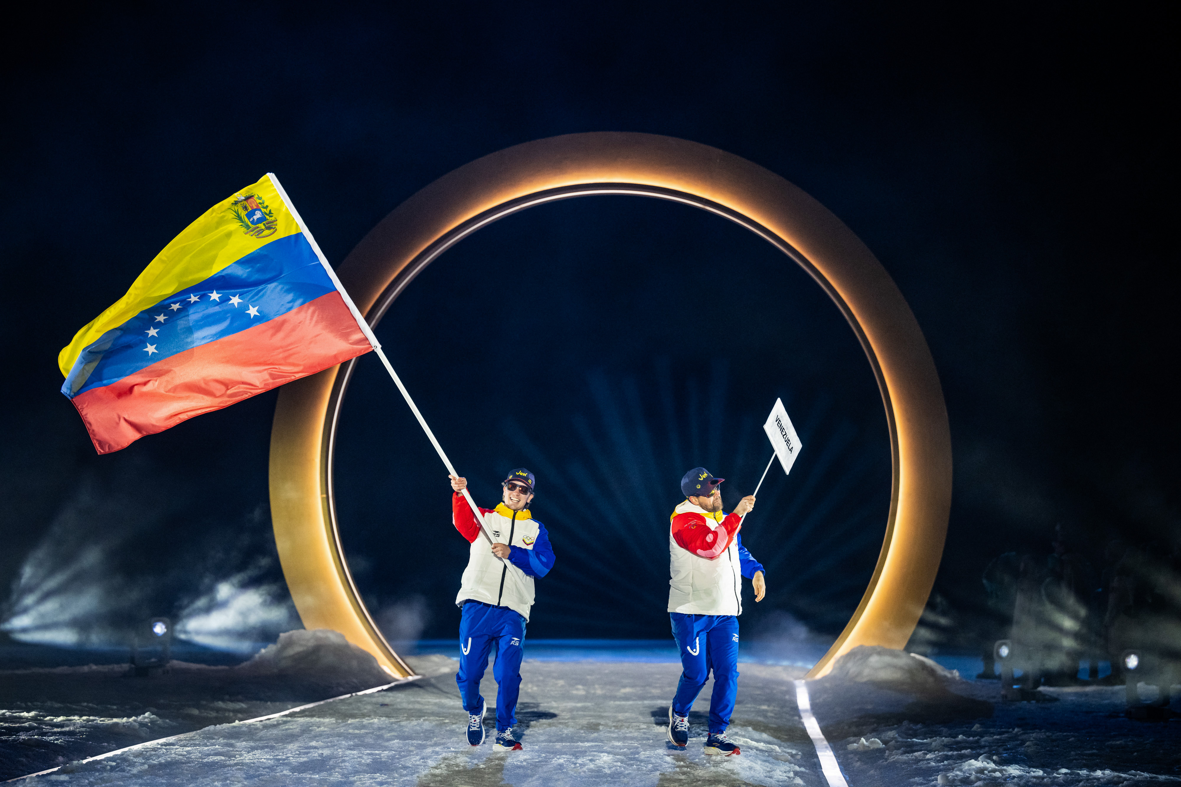 Nicolas Claveau-Laviolette, del equipo venezolano, y otros miembros del equipo ingresan al estadio durante la ceremonia inaugural de los Juegos Olímpicos de Invierno Milano Cortina 2026 en el Estadio de Salto de Esquí Predazzo, el 6 de febrero de 2026 en Val di Fiemme, Italia. | Fuente: Getty Images