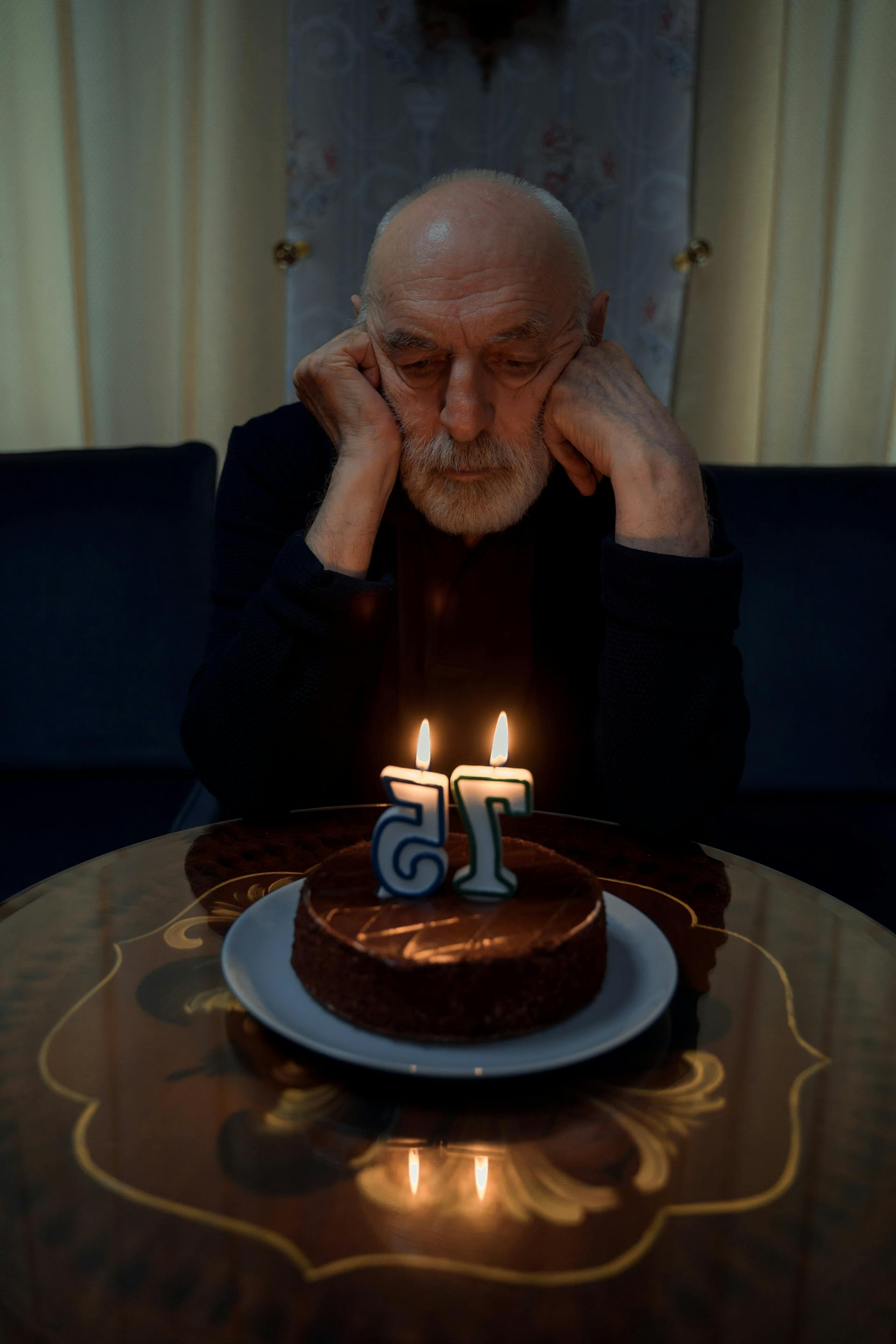 Sad old man looking at his birthday cake | Source: Pexels