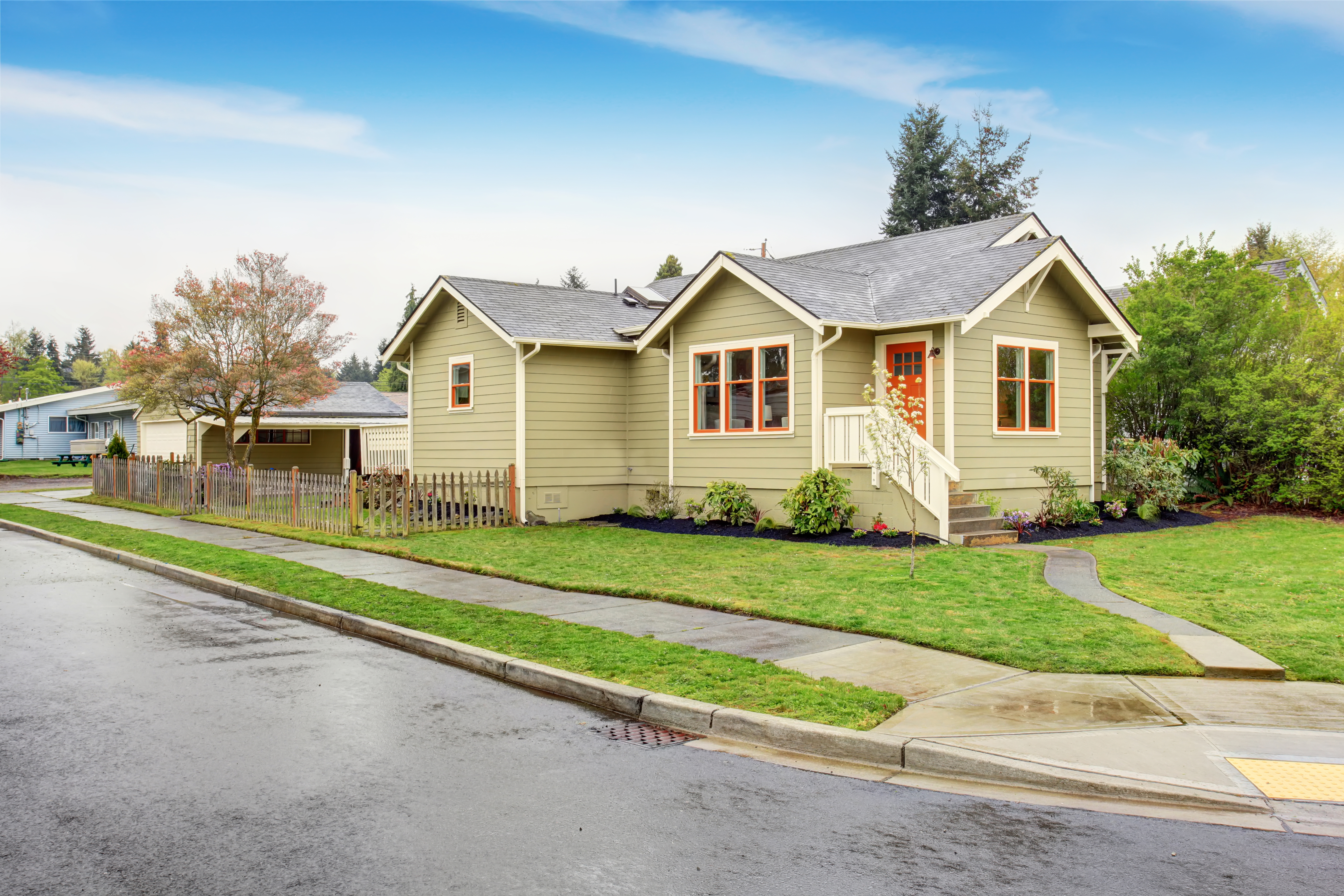 Antigua casita verde americana con porche. Césped verde alrededor y camino de entrada. | Fuente: Shutterstock
