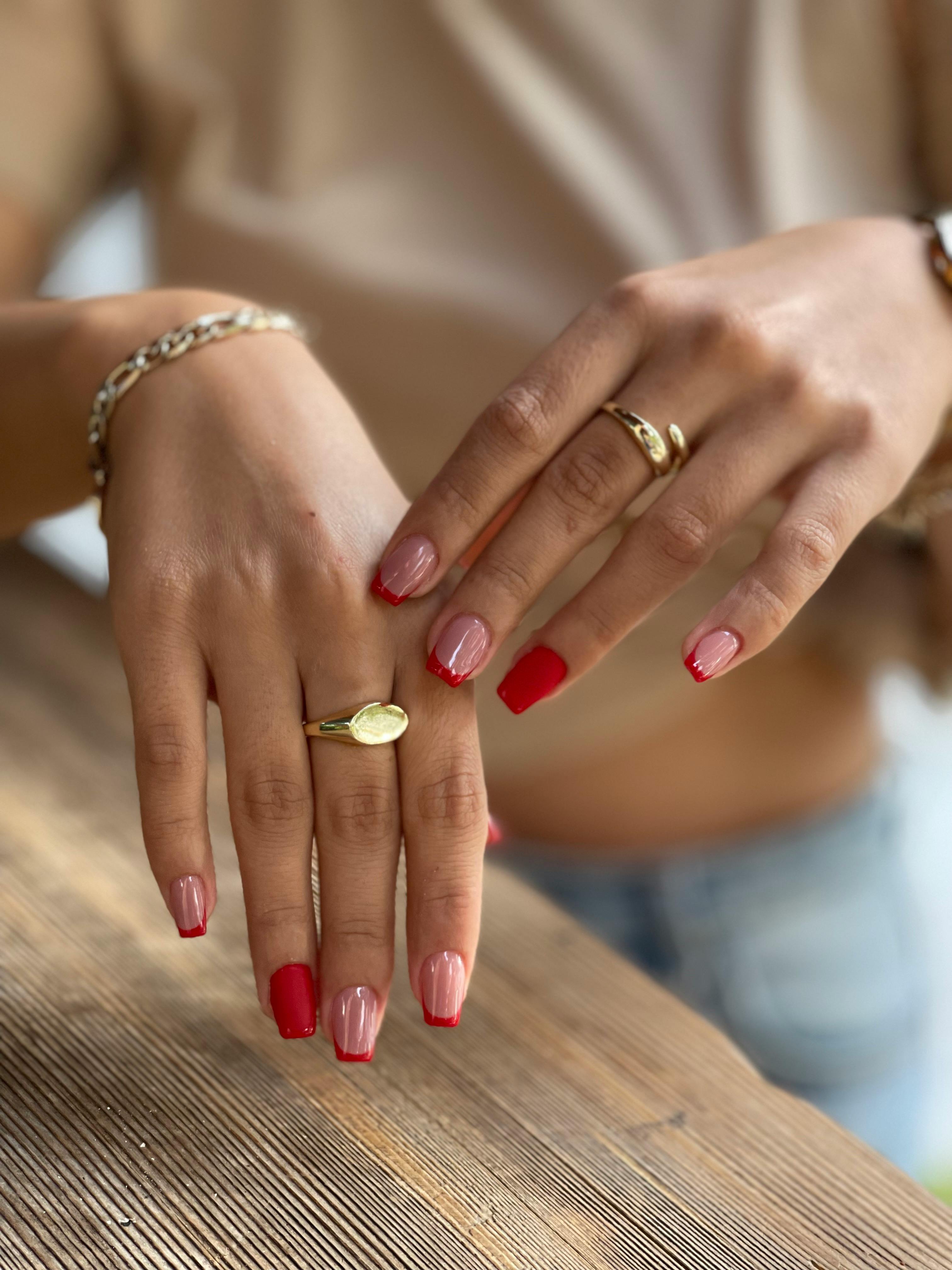 Mujer con esmalte de uñas francés y rojo | Fuente: Pexels