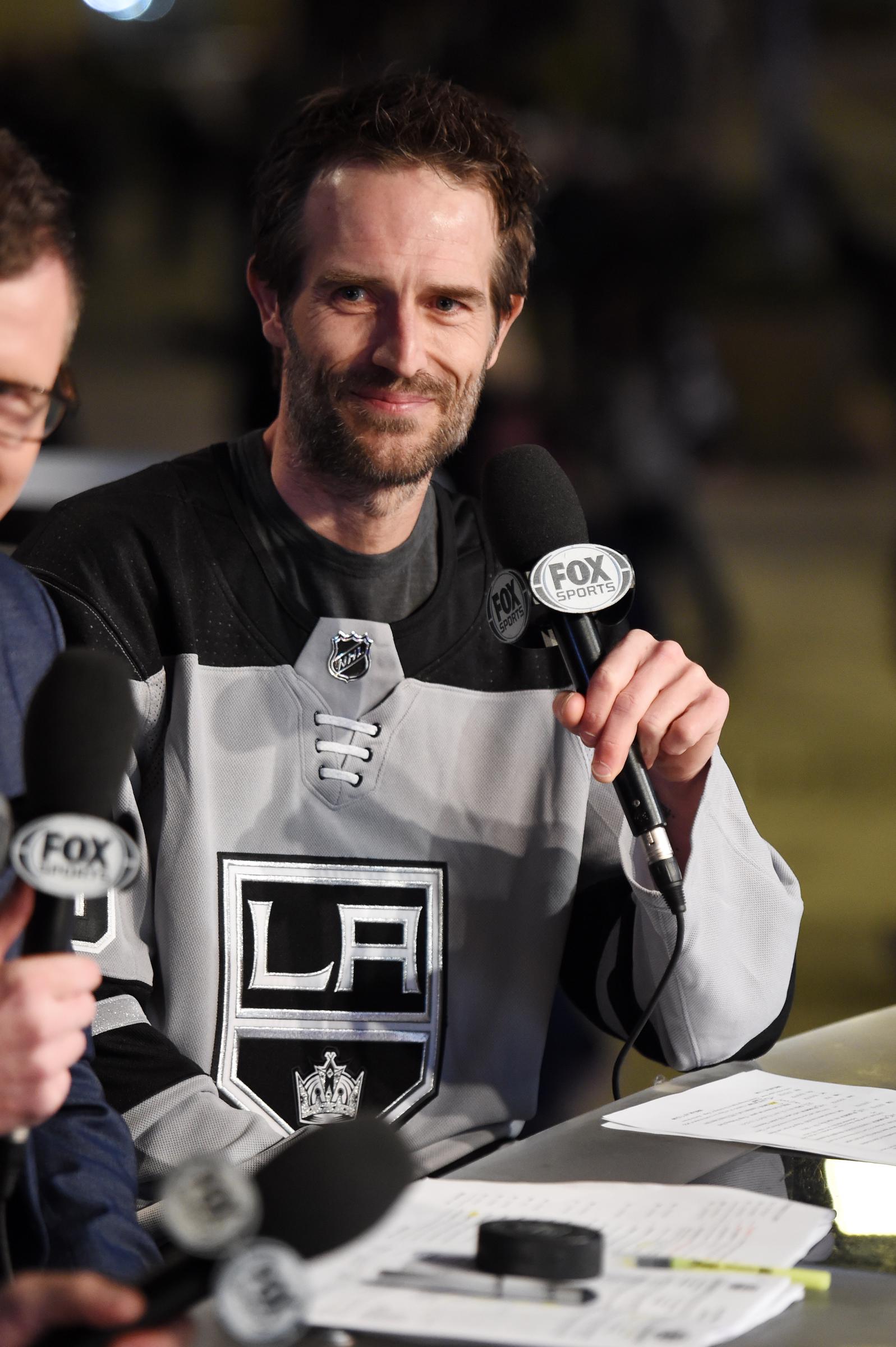 Vistiendo una camiseta de los Los Angeles Kings, Michael Vartan sonríe mientras se desempeña como invitado de honor célebre en un partido de la NHL. El actor lucía cómodo integrándose al mundo del deporte.
