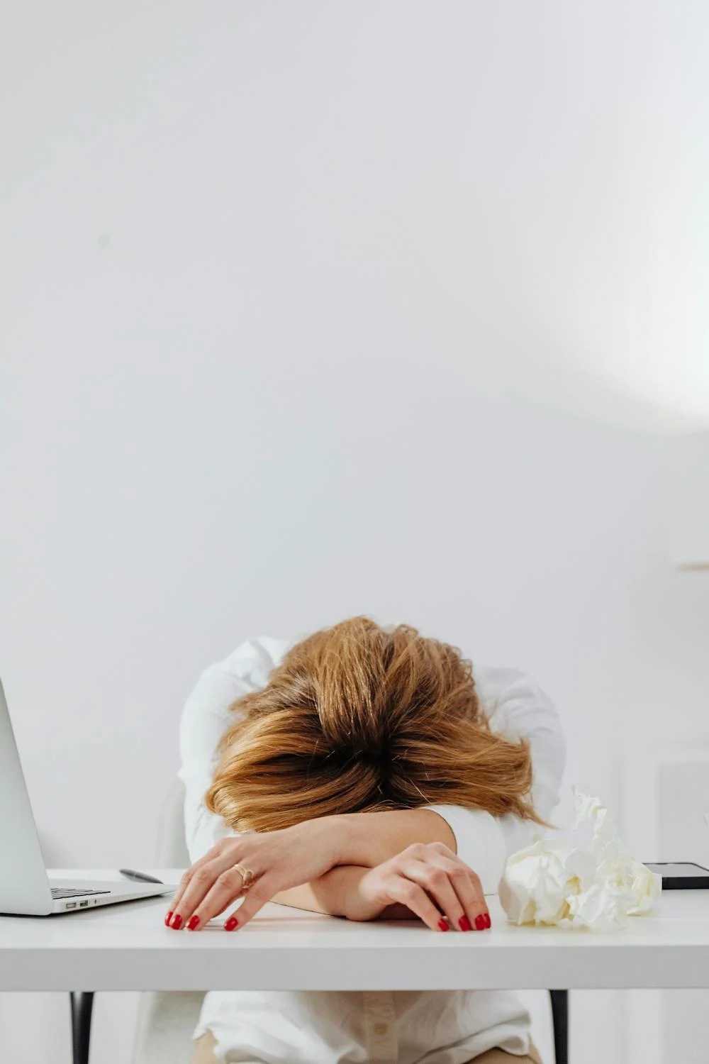 Una mujer cansada recostada sobre su mesa | Fuente: Pexels