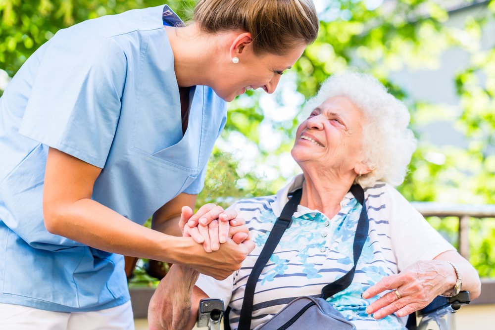 Enfermera toma de la mano a una mujer mayor en una pensión. | Fuente: Shutterstock.