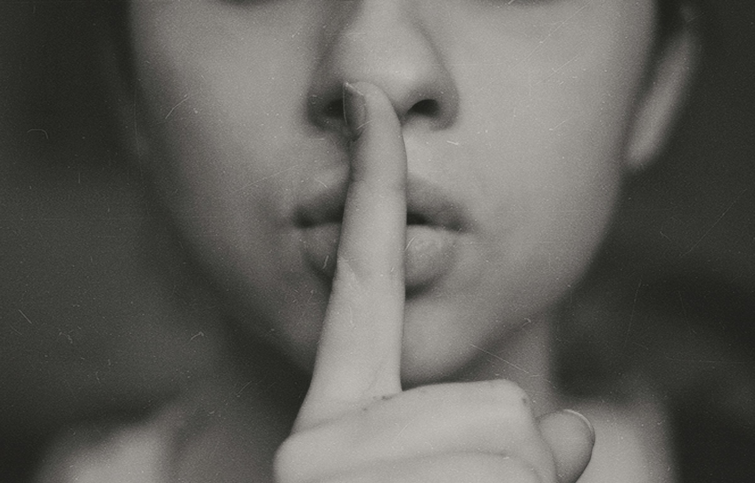 Foto en escala de grises de una mujer haciendo un signo silencioso con la mano | Fuente: Unsplash