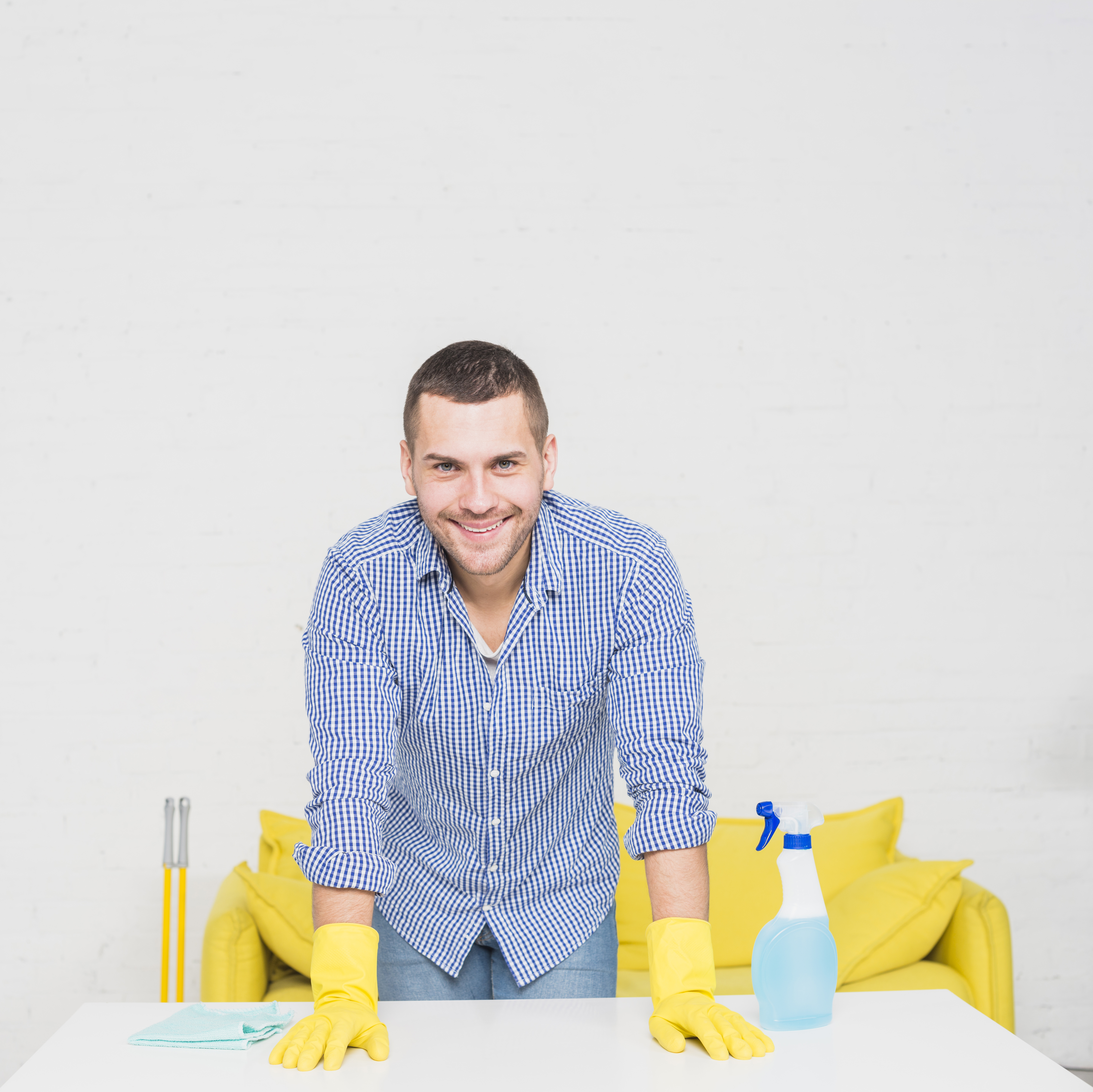 Hombre sonriendo mientras está rodeado de materiales de limpieza | Fuente: Freepik