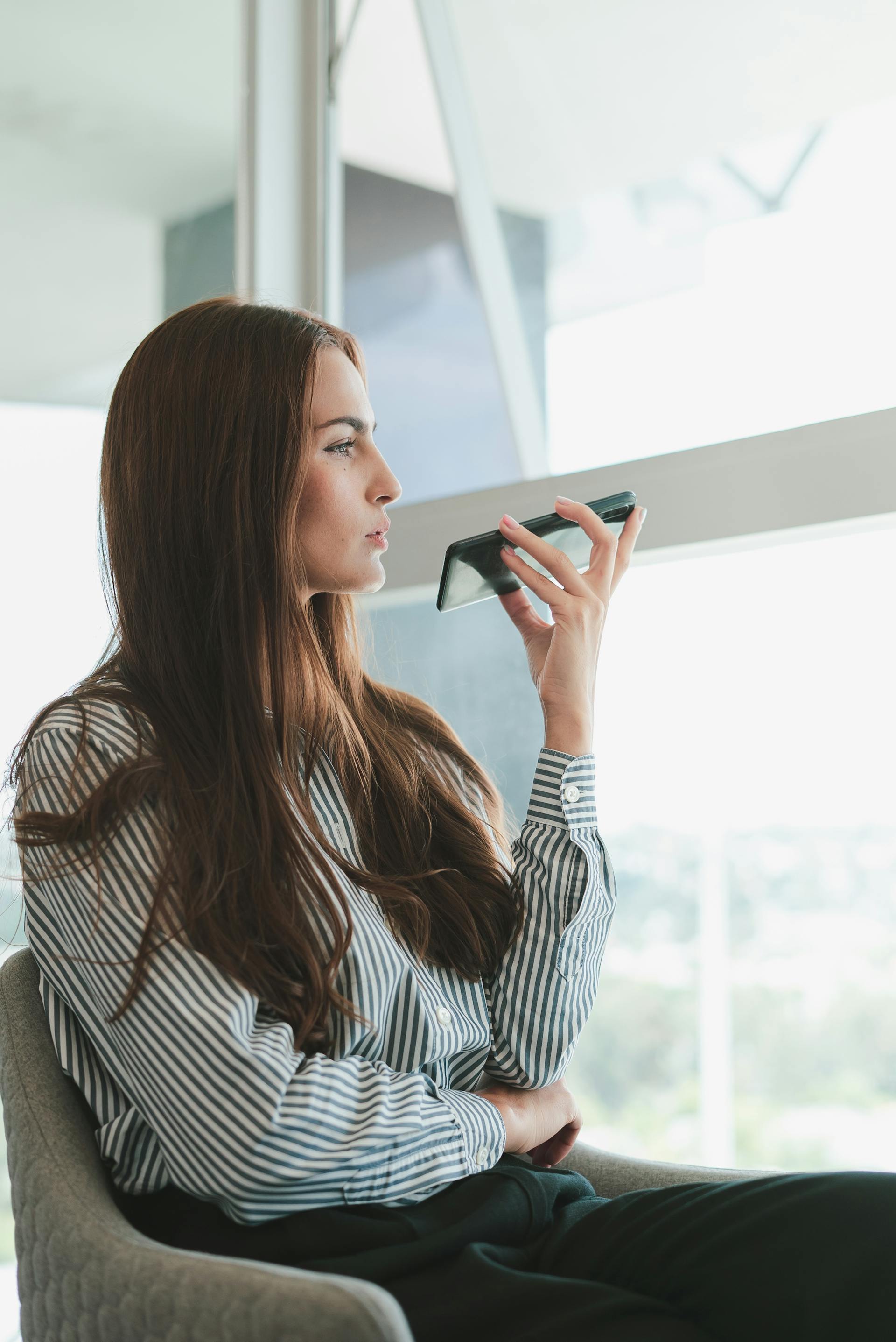 Una mujer sentada en una silla y hablando por teléfono | Fuente: Pexels