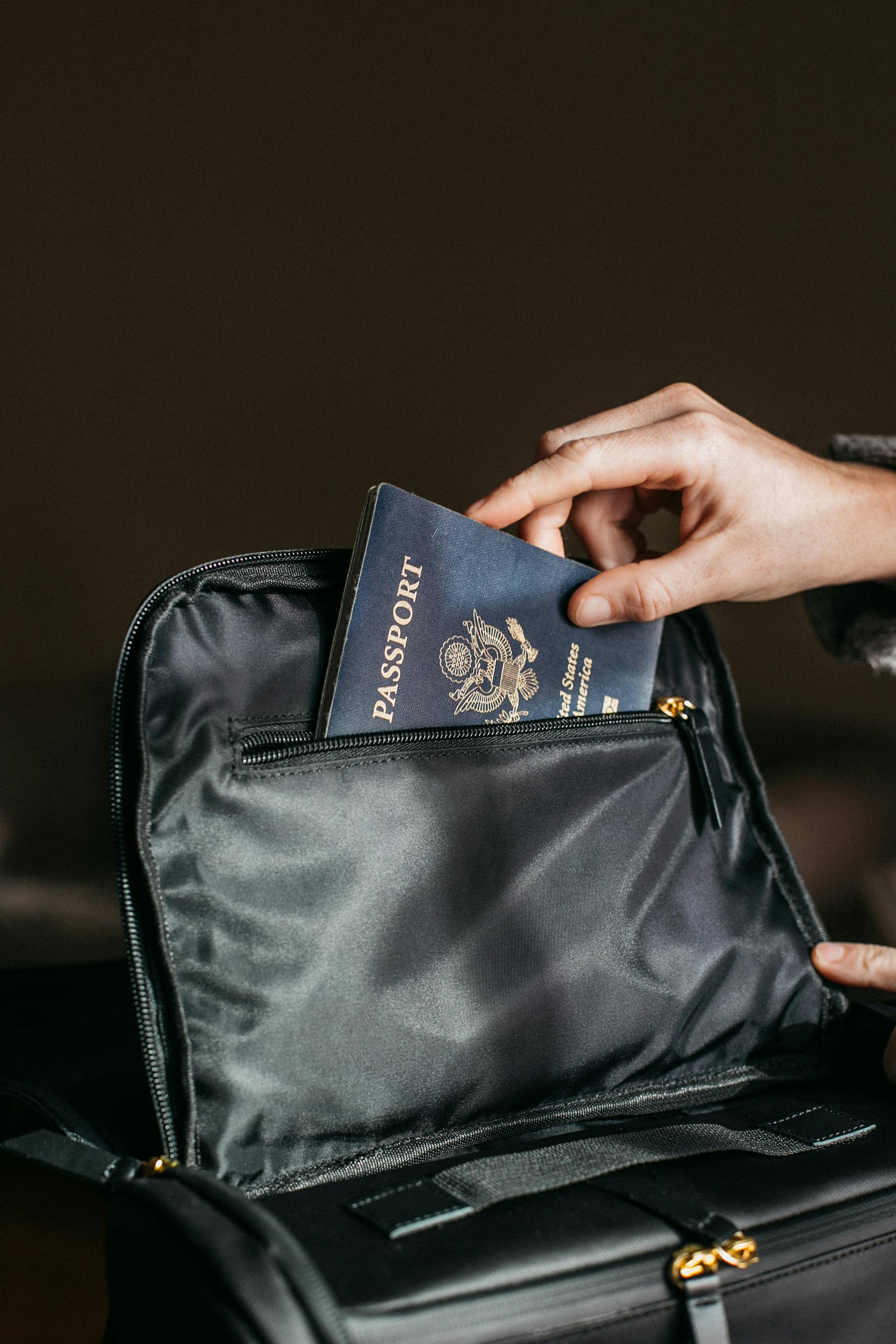 Primer plano de una persona metiendo un pasaporte en una bolsa negra | Fuente: Pexels