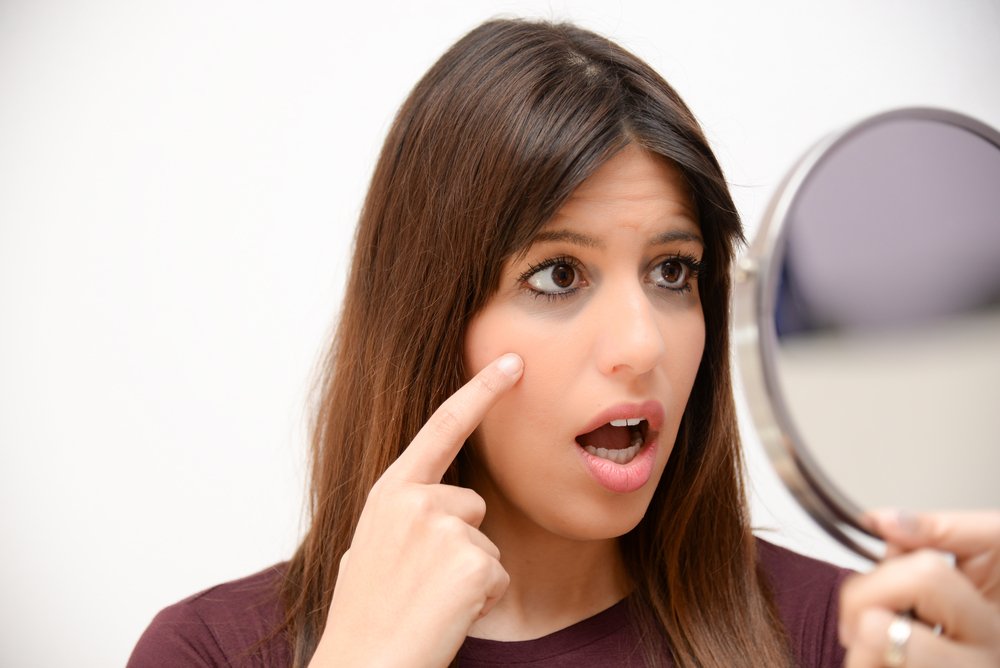 Mujer sorprendida viendo sus ojeras en el espejo. | Foto: Shutterstock