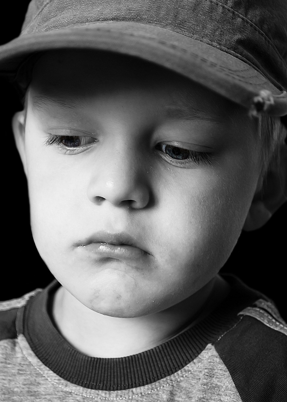 Retrato en escala de grises de un niño triste con los ojos bajos | Fuente: Pixabay