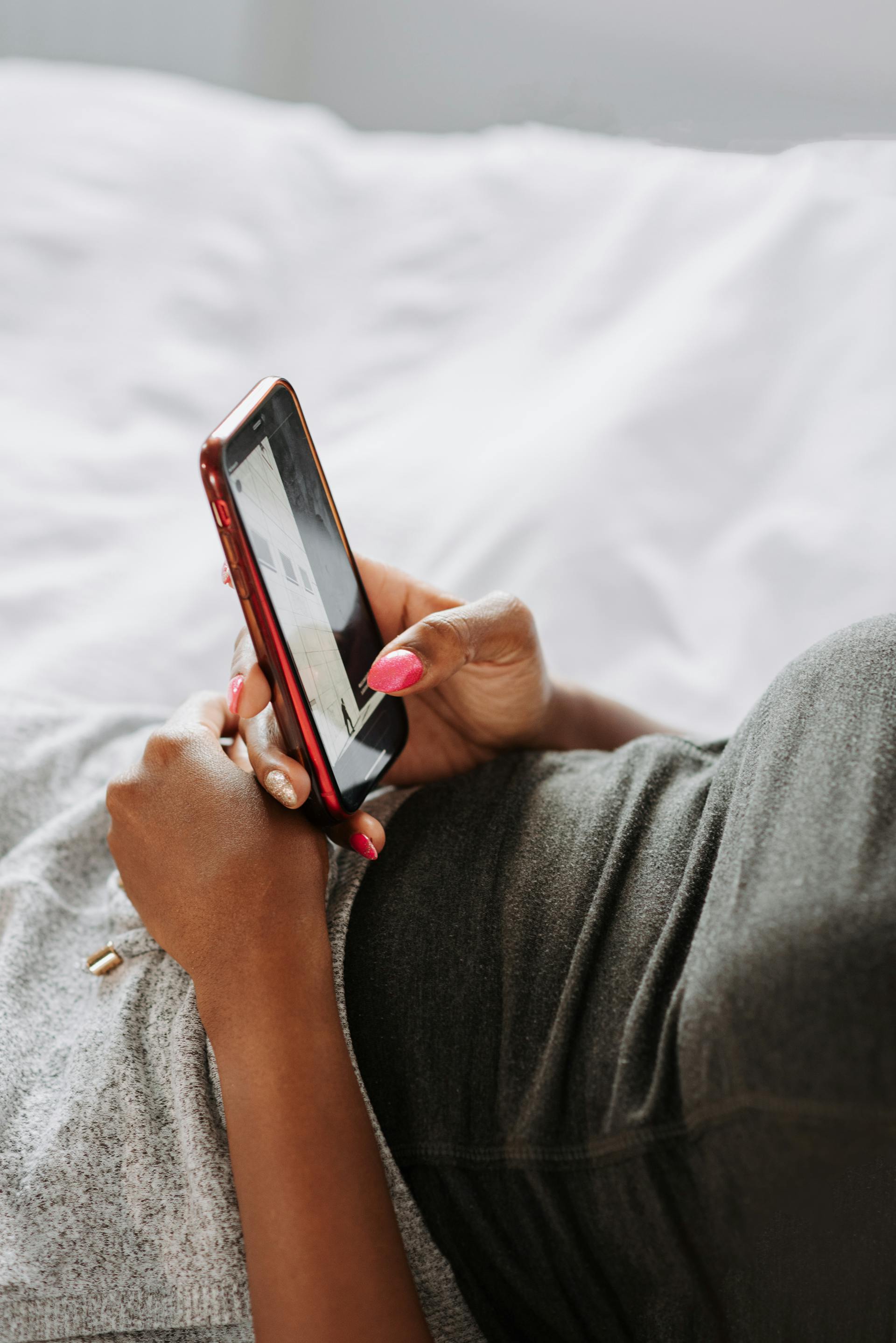 Una mujer usando su teléfono en la cama | Fuente: Pexels