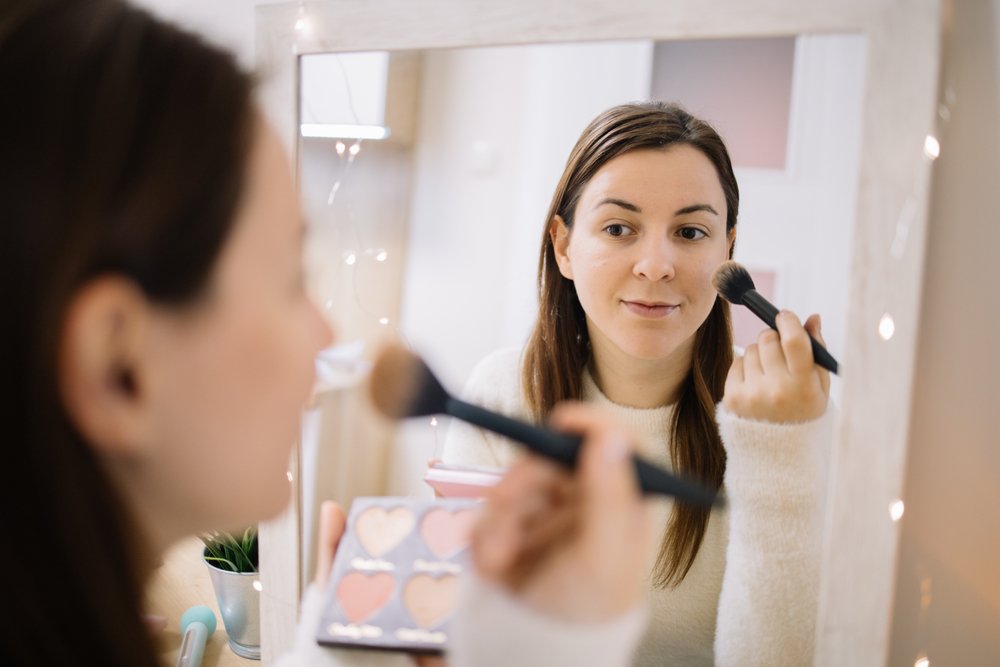 Mujer frente al espejo maquillándose. | Foto: Shutterstock