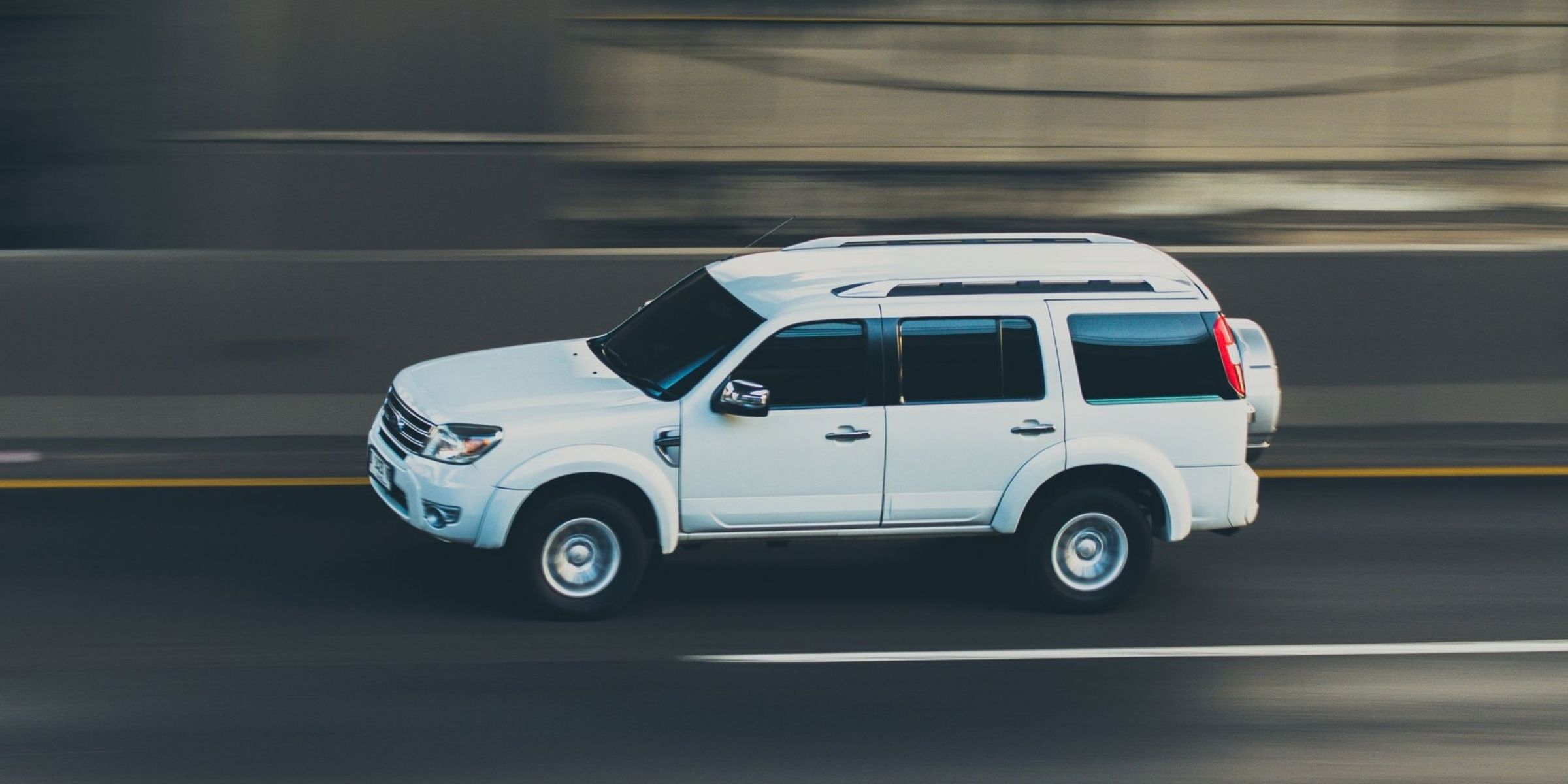 Un todoterreno blanco circulando a toda velocidad por una carretera | Fuente: Pexels