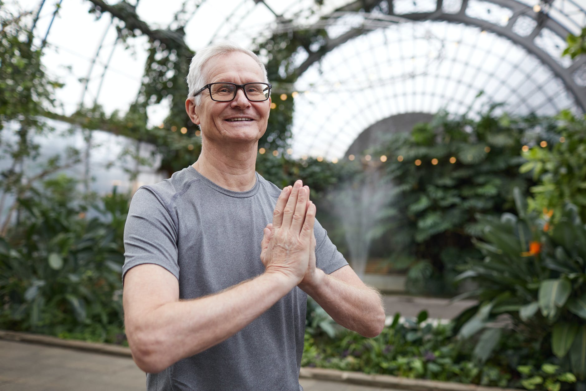 Hombre mayor sonriendo con sus manos juntas dentro de un invernadero. | Foto: Pexels