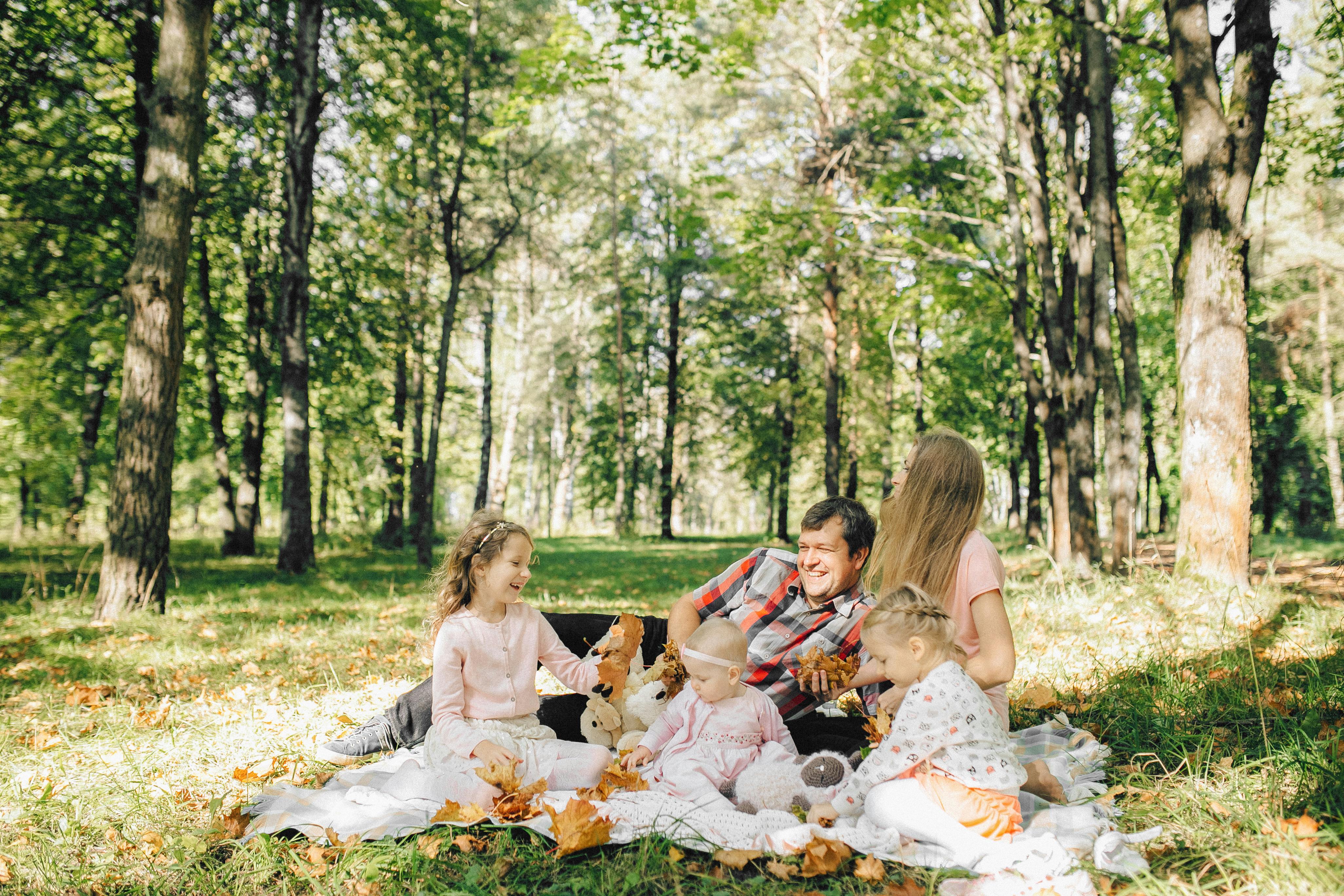 Unos padres y sus tres hijos pequeños disfrutando de un picnic | Fuente: Pexels