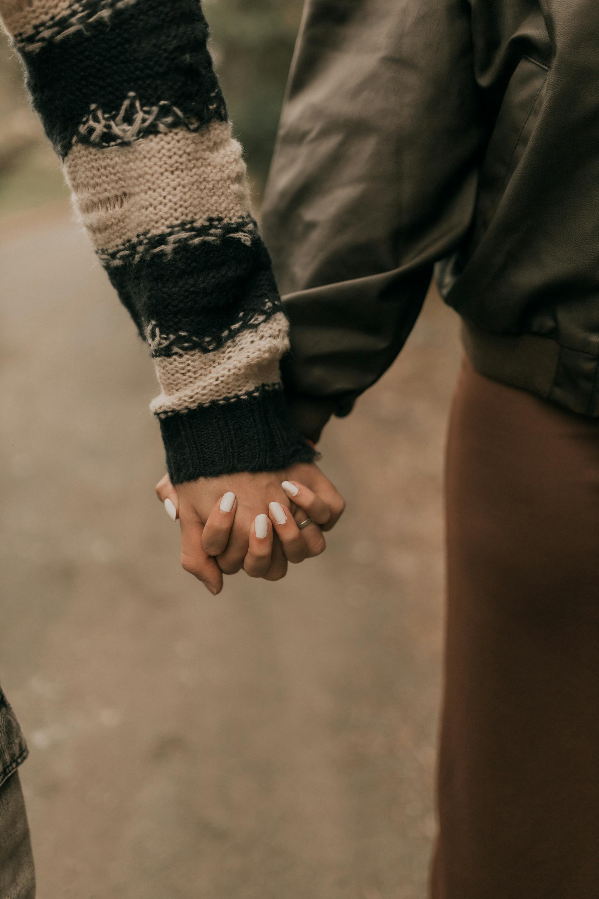 Pareja tomada de la mano al aire libre | Fuente: Pexels