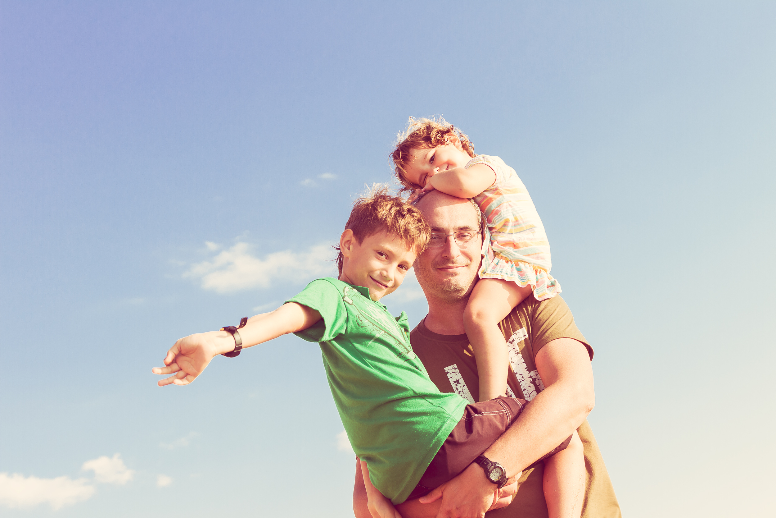 Un padre con su hijo en brazos y su hija sobre los hombros | Foto: Shutterstock