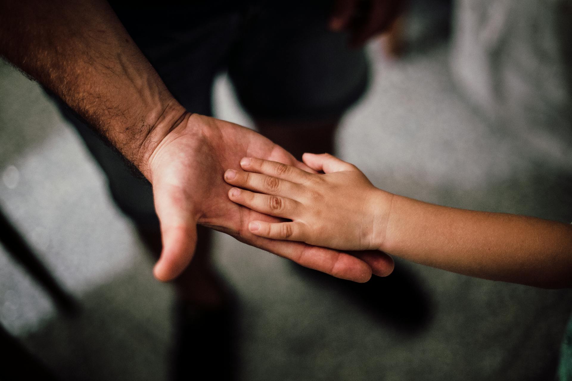 La mano de un niño apoyada en la de su padre | Fuente: Pexels