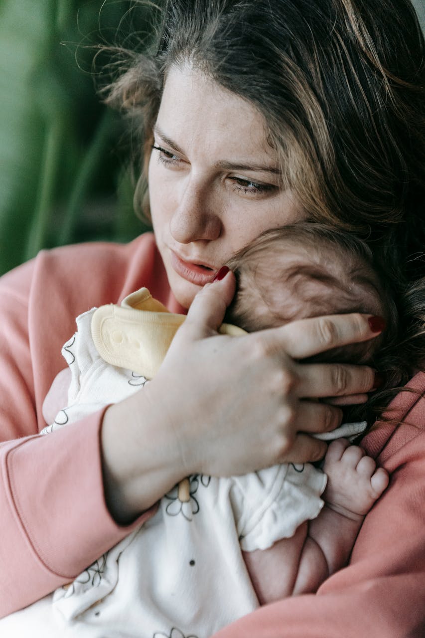 Una madre perdida en profundos pensamientos mientras sostiene a su bebé | Fuente: Pexels